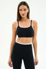 A woman modeling a black sports bra and matching high-waisted leggings with white trim, photographed against a clean white studio background.