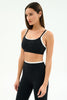 Woman wearing a black sports bra and leggings on a white background