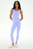 A woman modeling a matching light purple athletic set consisting of a sleeveless tank top and high-waisted leggings, paired with white sneakers, against a plain white studio background.