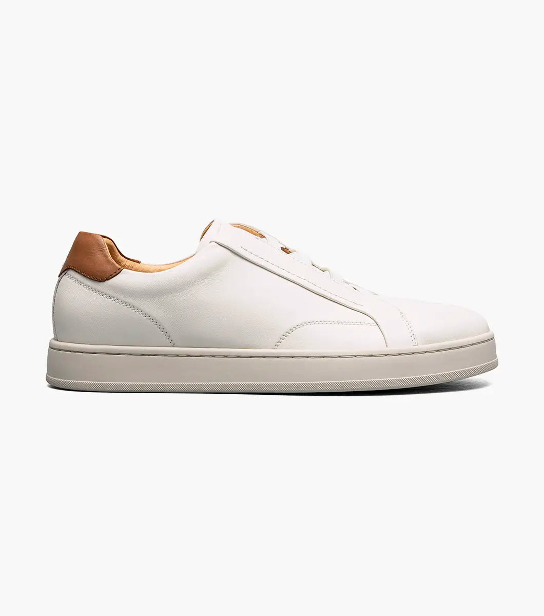 A white leather low-top sneaker with a light brown leather heel tab and a thick off-white rubber sole, shown in a side profile on a light gray background.