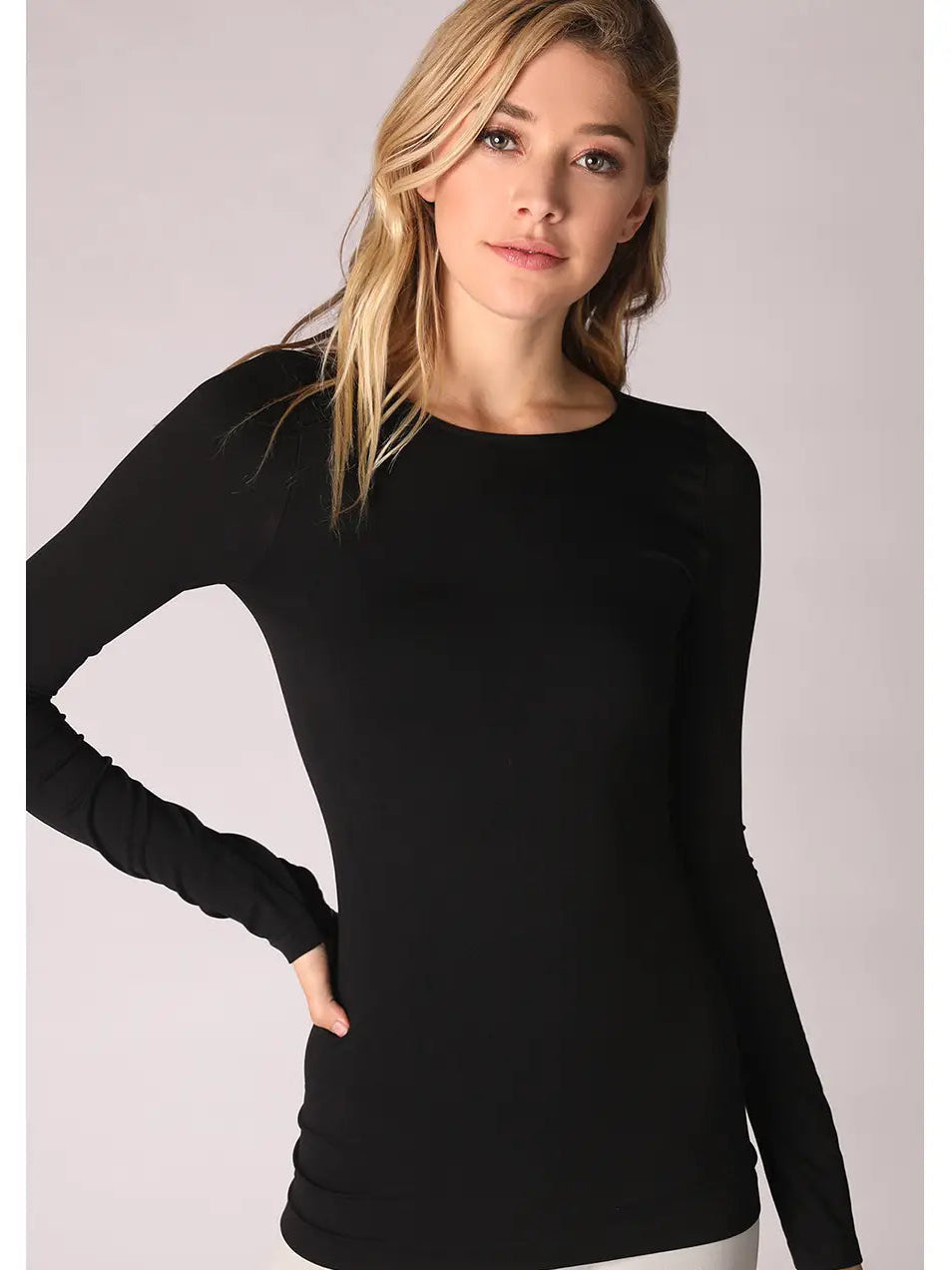 A woman modeling a fitted black long-sleeve crewneck top against a light gray studio background. 