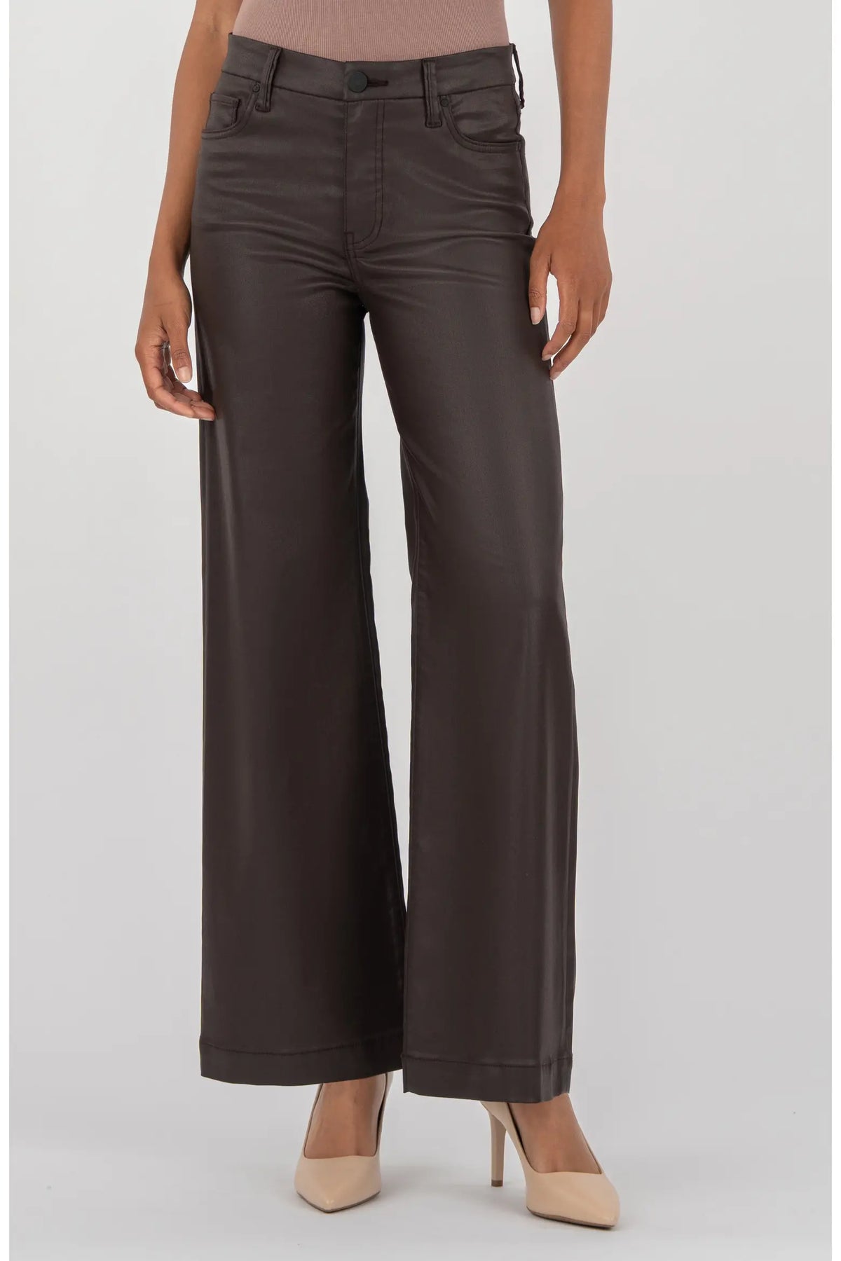 A model wearing dark brown wide-leg faux leather pants, paired with a dusty rose top and beige heels, against a light gray studio background.