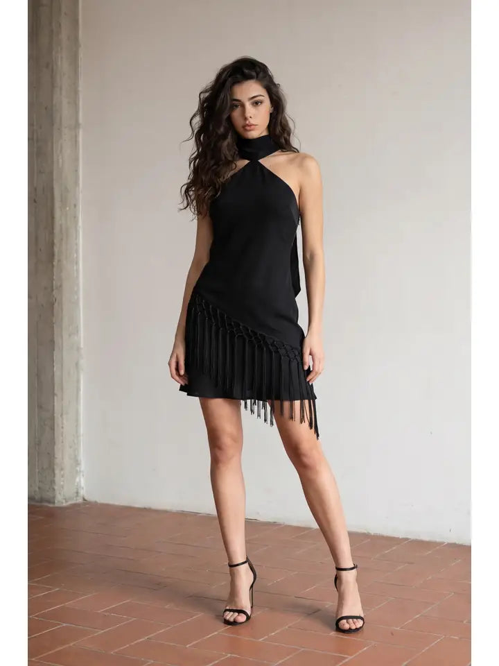 Woman standing in front of white wall wearing a black mini dress