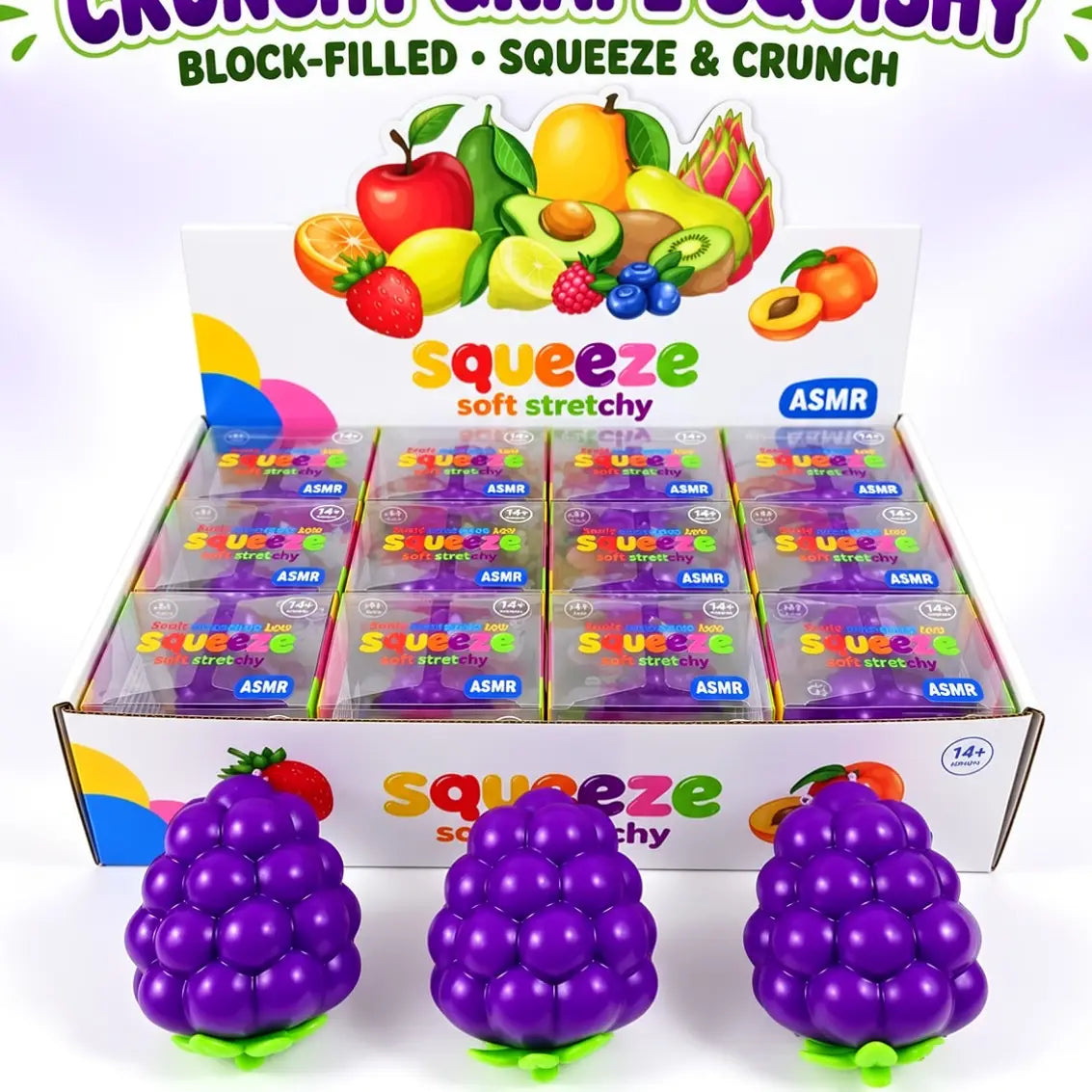 A display box filled with small packaged squeeze balls, with three large purple grape-shaped squeeze balls in front. The packaging and header card feature colorful fruit illustrations and the text 'Squeeze soft stretchy' and 'ASMR'.