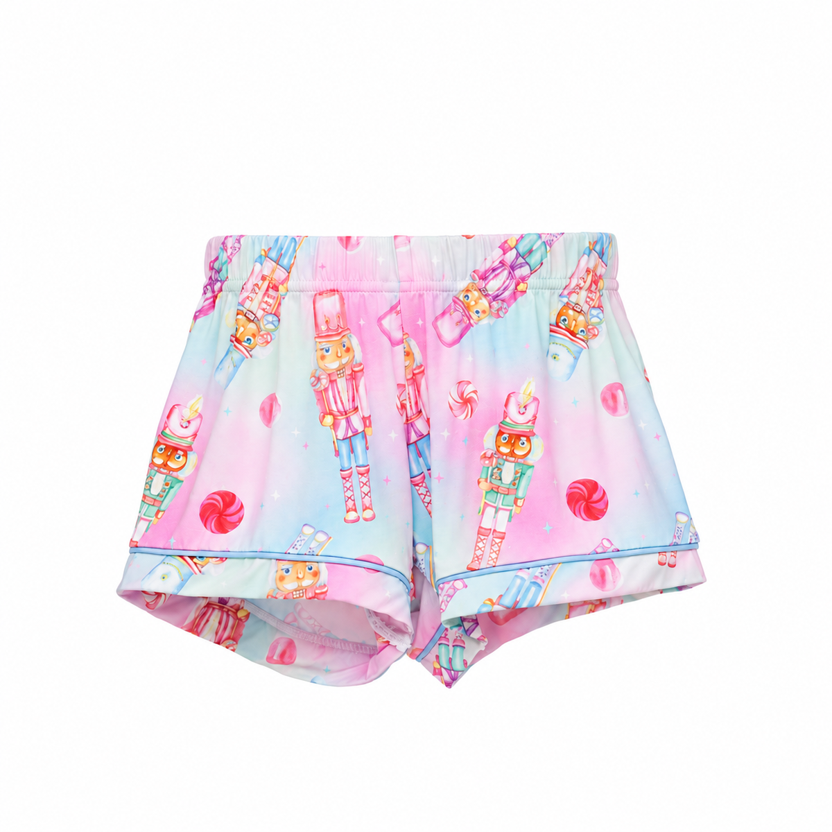 A pair of pastel pink and blue shorts featuring a whimsical print of nutcrackers, candy canes, and lollipops, displayed flat against a solid white background.