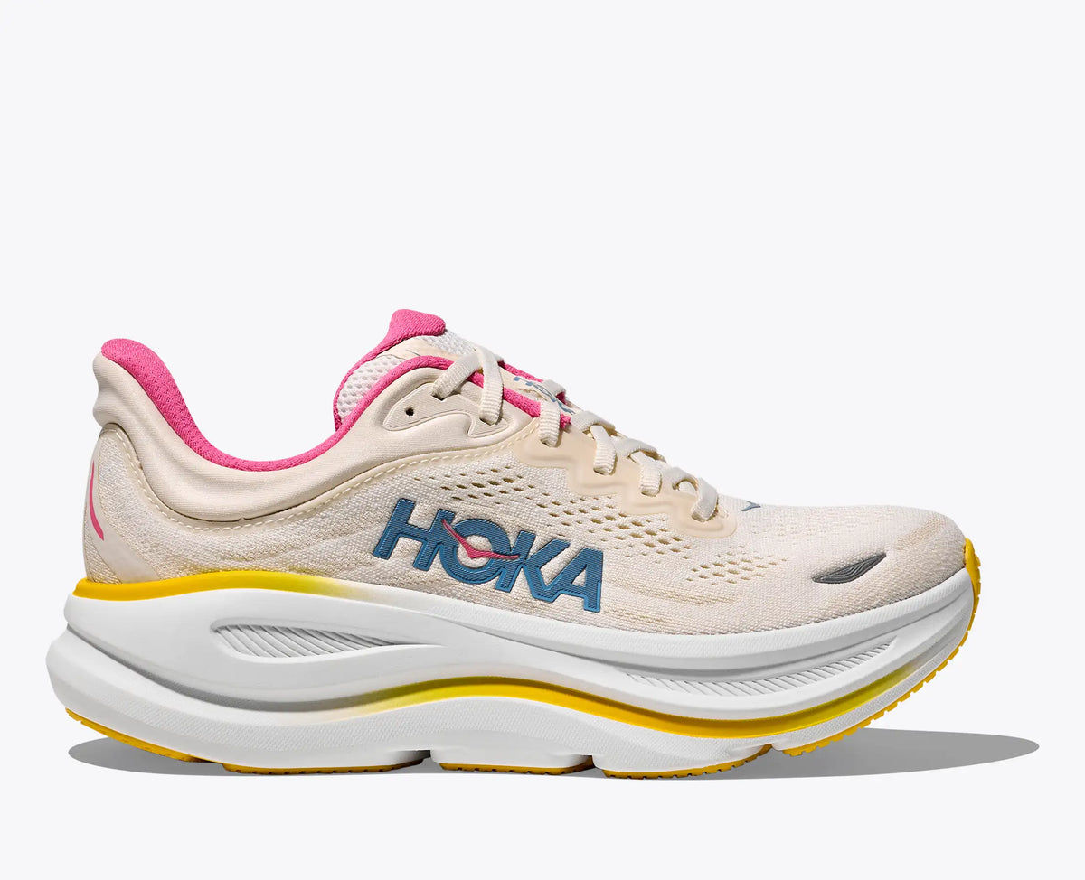 Beige running shoe with pink accents and 'Hoka' branding on a white background
