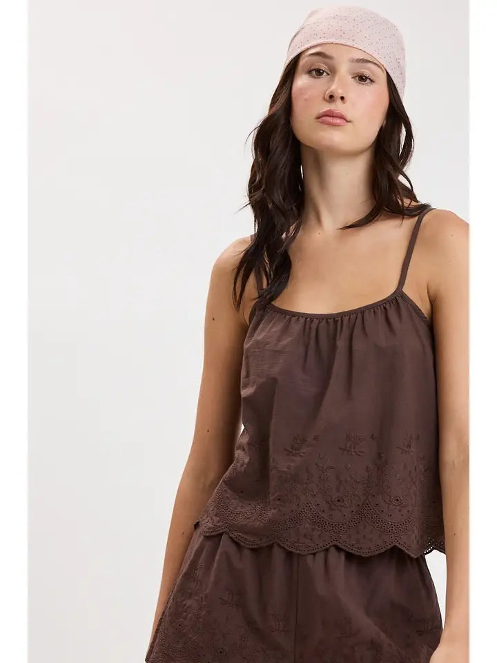woman standing on white background wearing a brown tank top 