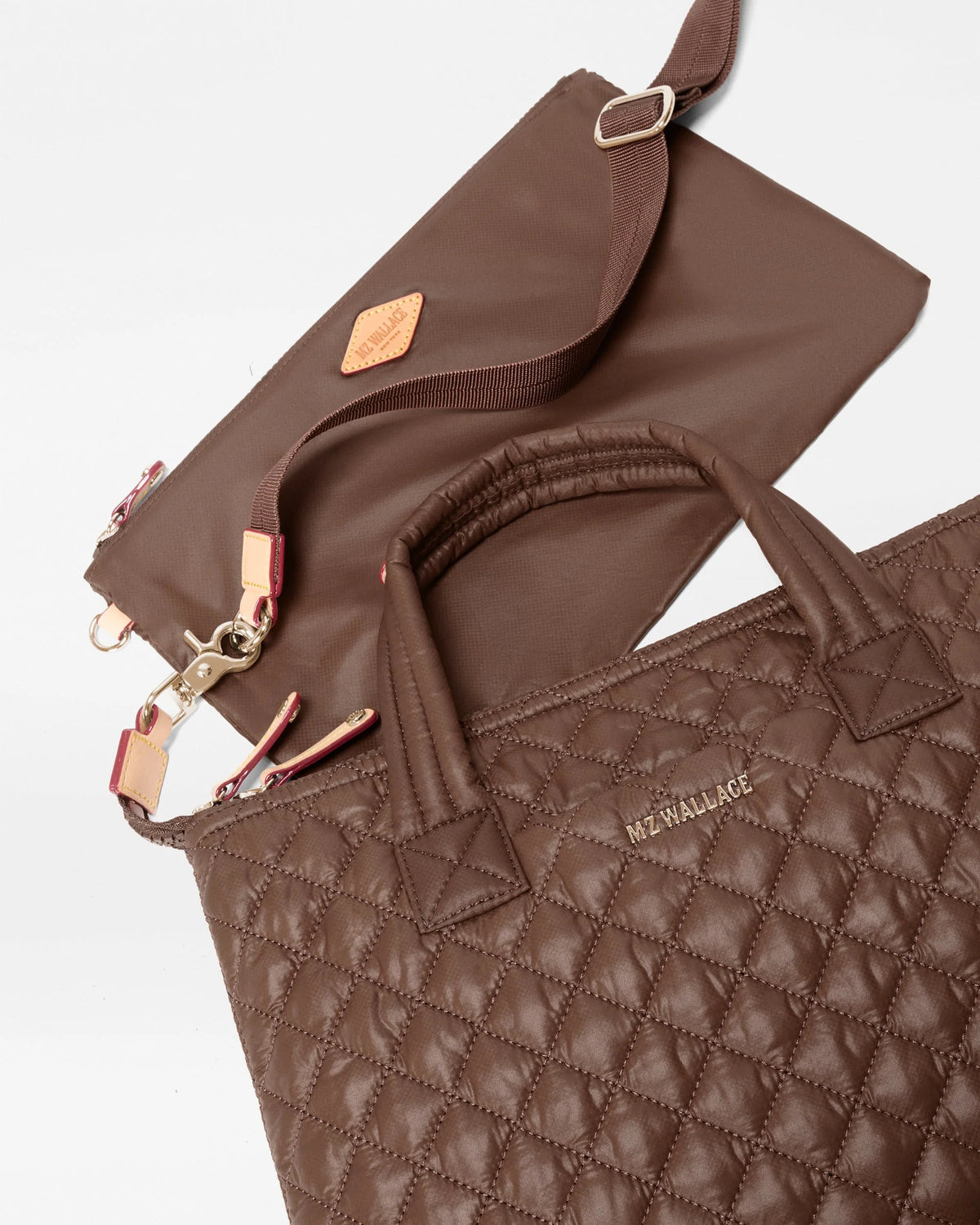 A brown quilted tote bag with top handles and a matching zip pouch, both featuring a diamond-quilted pattern and small tan leather brand patches, photographed on a clean white background. The tote bag has 'ALEXANDRA' printed in gold on the front.