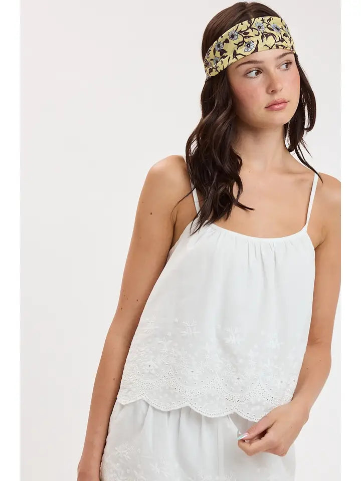 woman standing on white background wearing a white tank top 