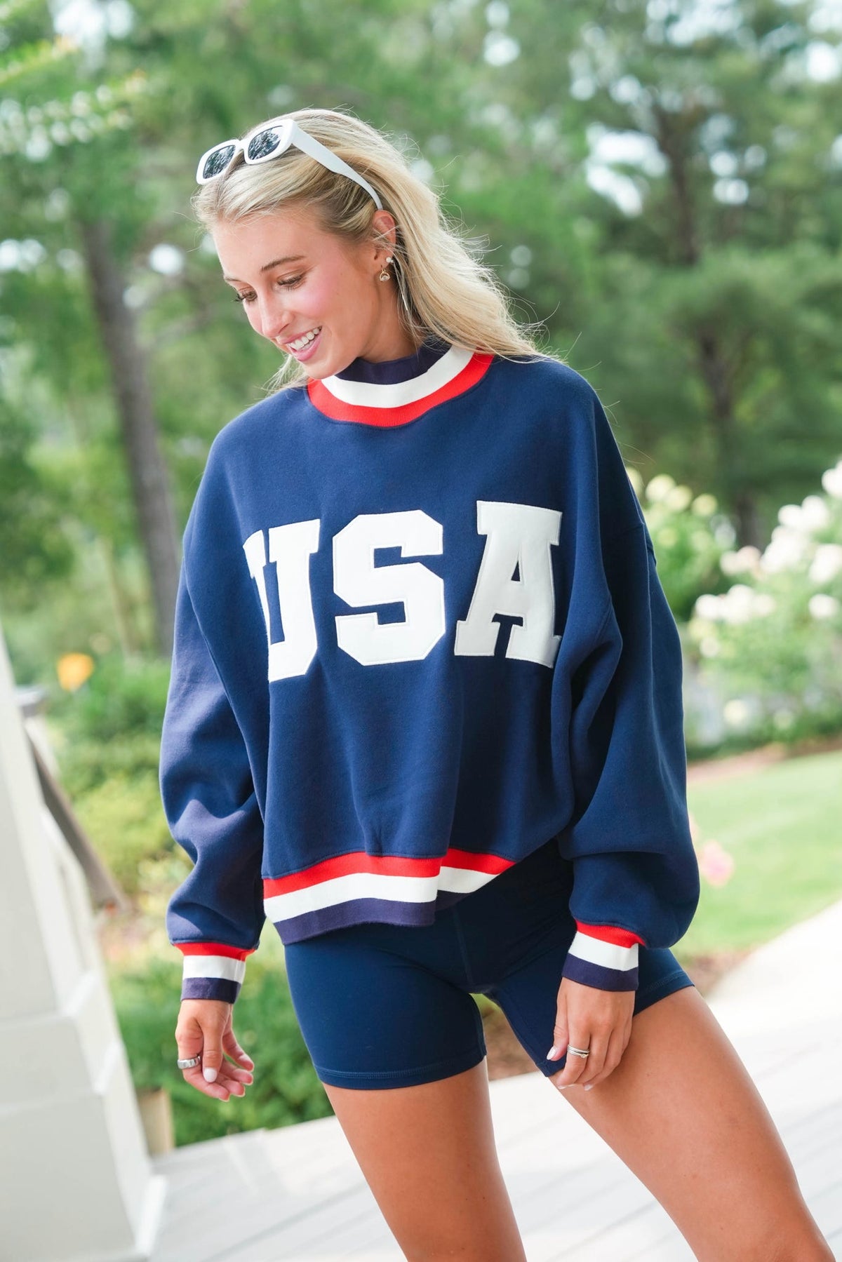 Woman wearing a blue 'USA' sweatshirt with red and white accents outdoors.
