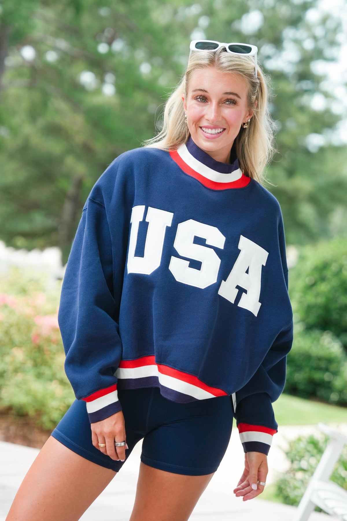 Woman wearing a blue 'USA' sweatshirt with red and white accents outdoors.