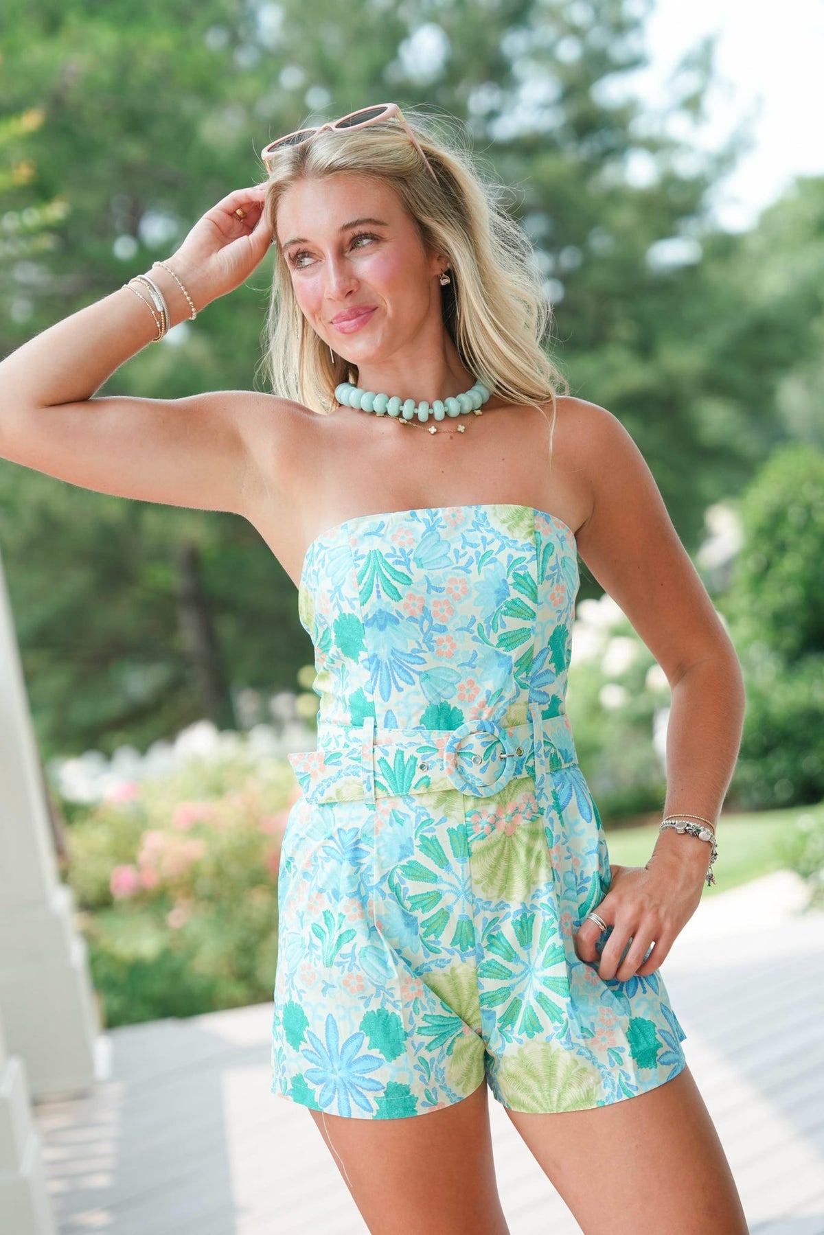 Woman wearing a strapless floral romper with a blurred garden background