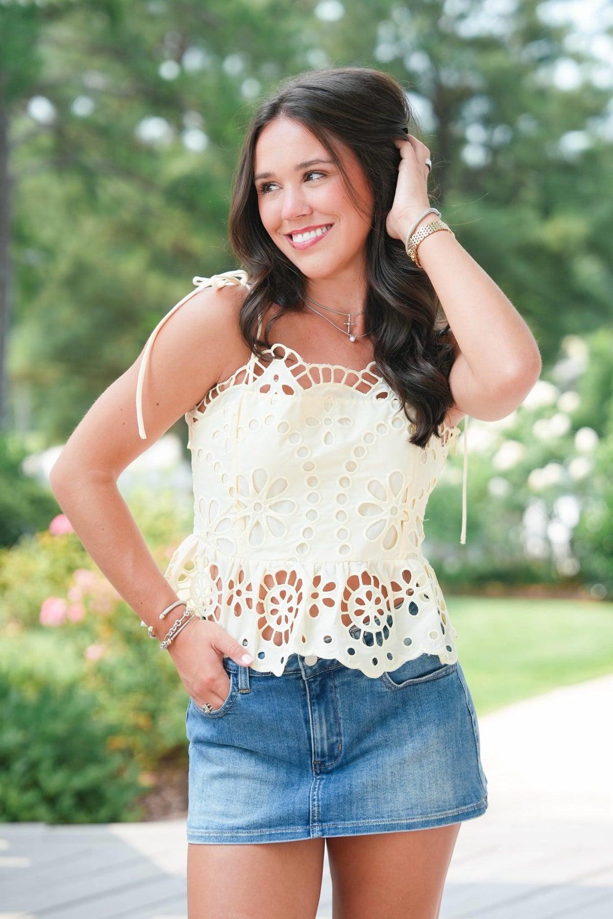 Woman wearing a white lace top and blue denim skirt outdoors