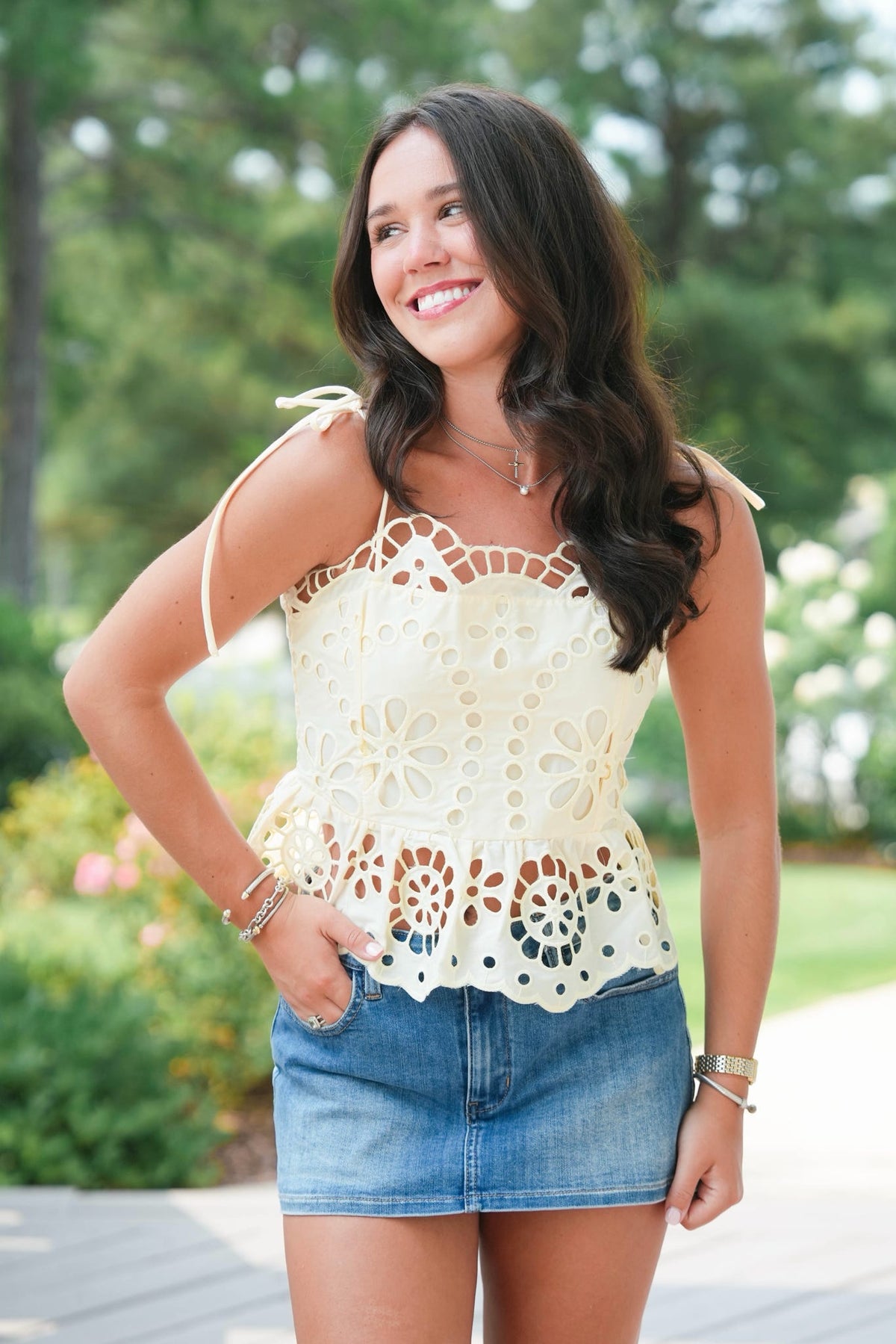 Woman wearing a white lace top and denim shorts outdoors