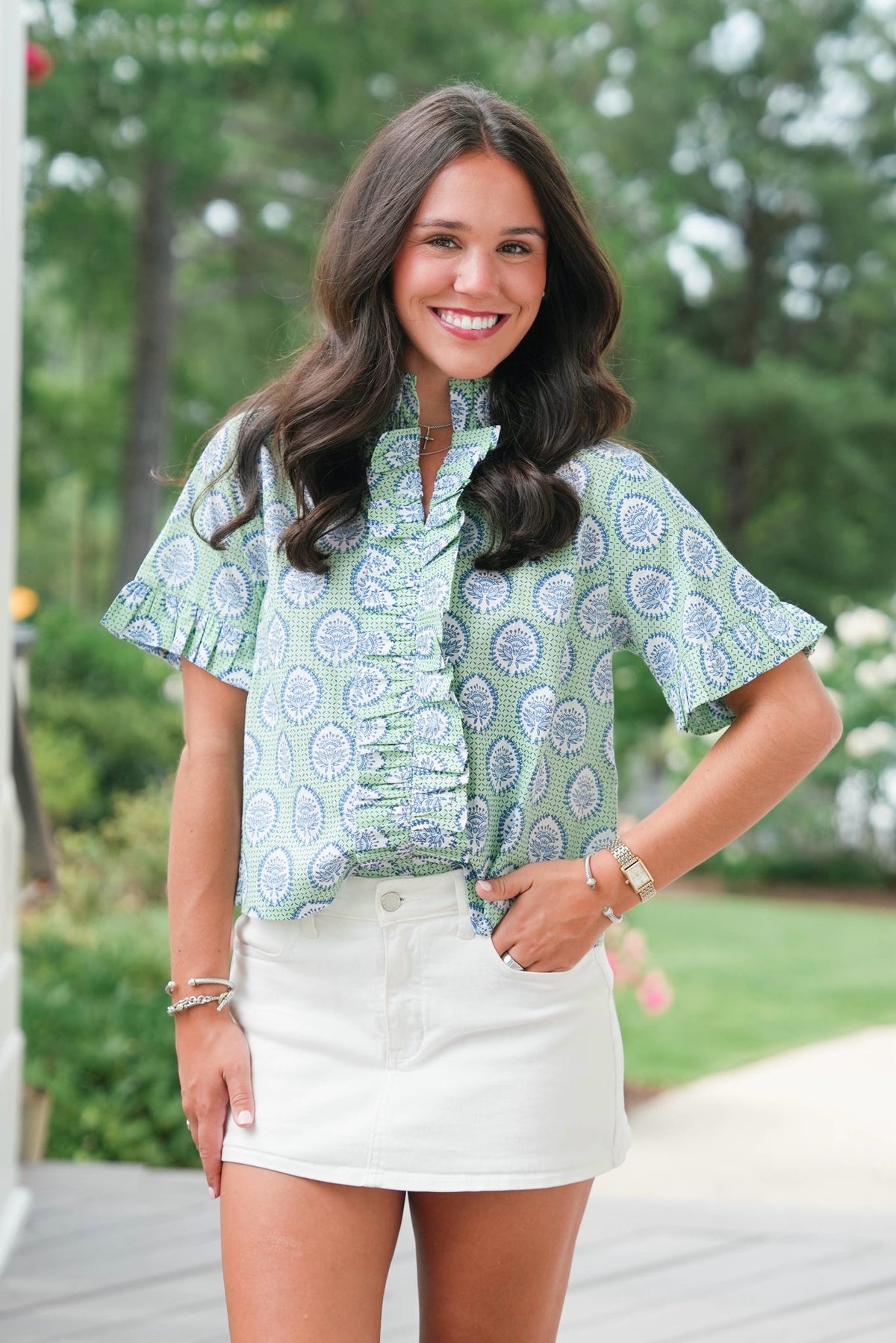 Woman wearing a green patterned shirt and white shorts outdoors