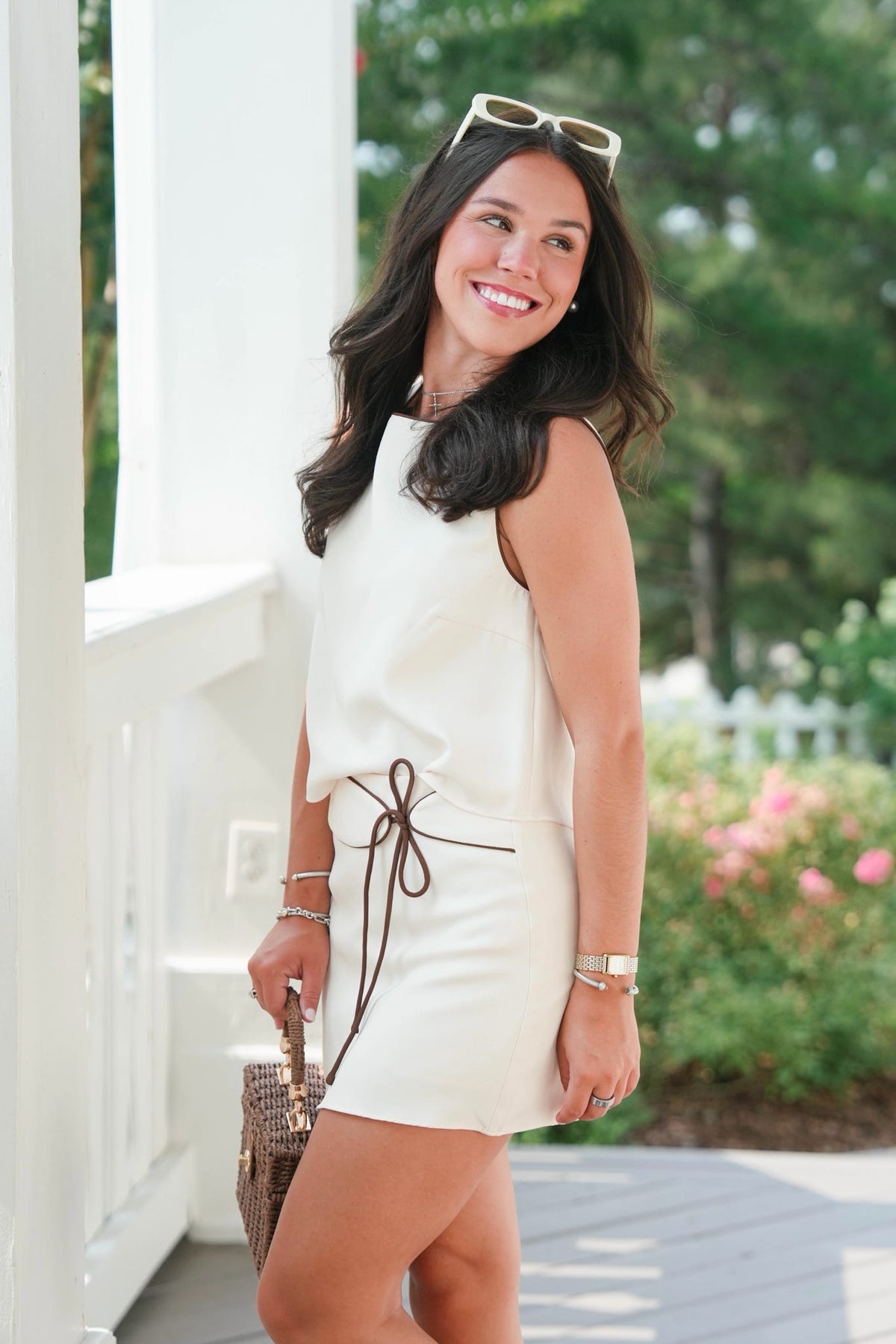Woman in a white dress standing outdoors with greenery in the background