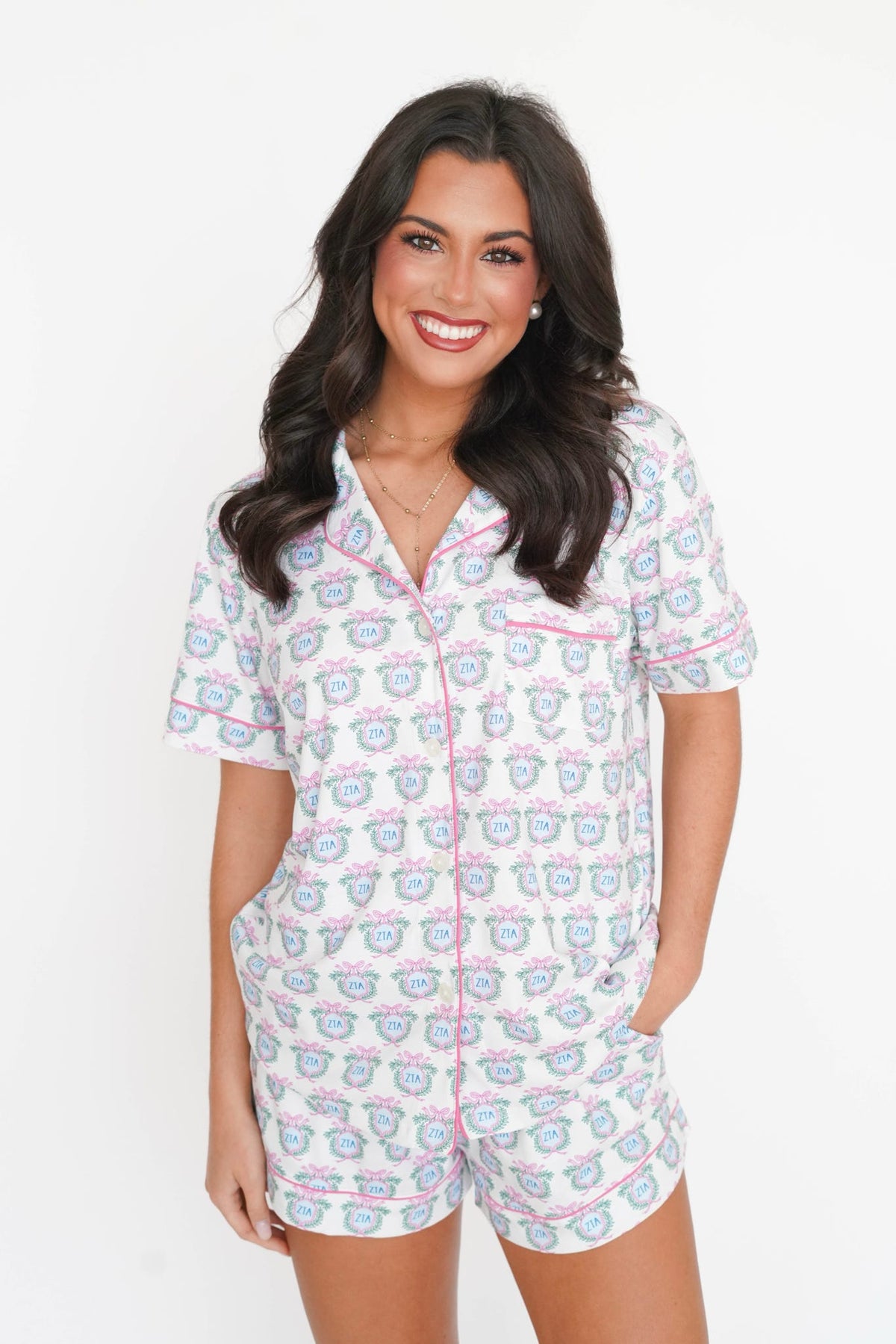 A woman modeling a short-sleeve pajama set with a white base and a repeating pink and blue teddy bear pattern, set against a plain white background.