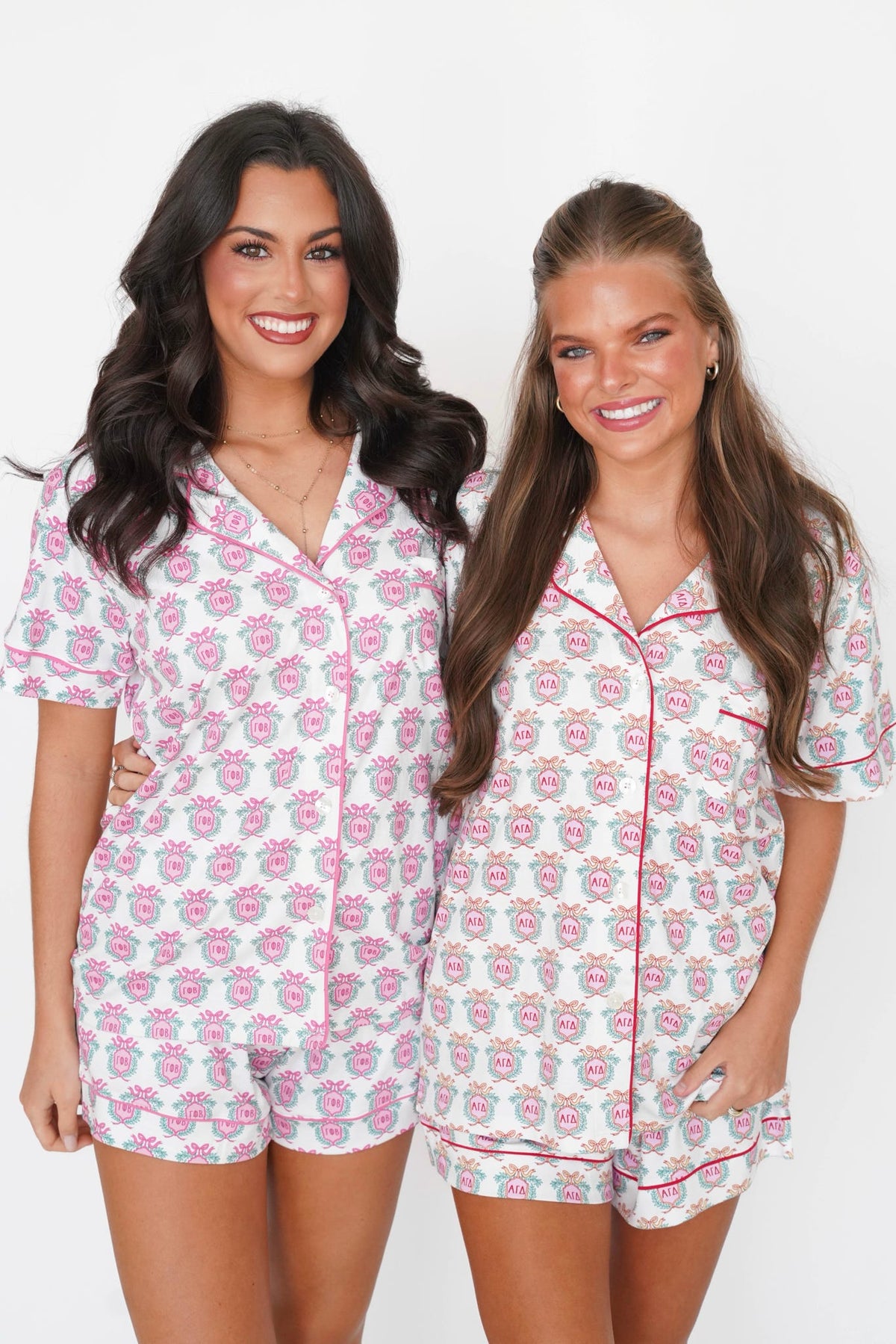 Two women modeling matching short-sleeve pajama sets with a pink and green floral pattern on a white background, standing against a plain white studio backdrop.