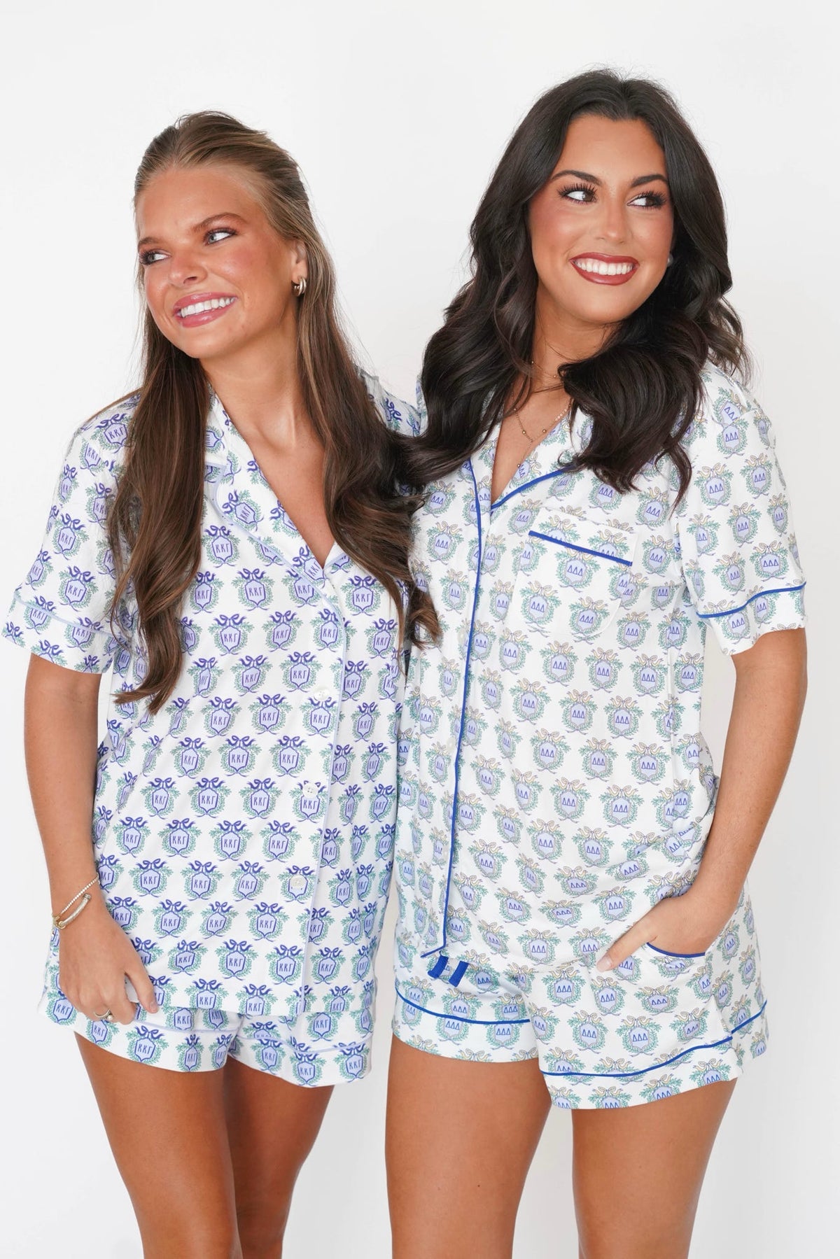 Two women modeling matching short-sleeve pajama sets with a blue and white floral pattern, standing against a plain white background.