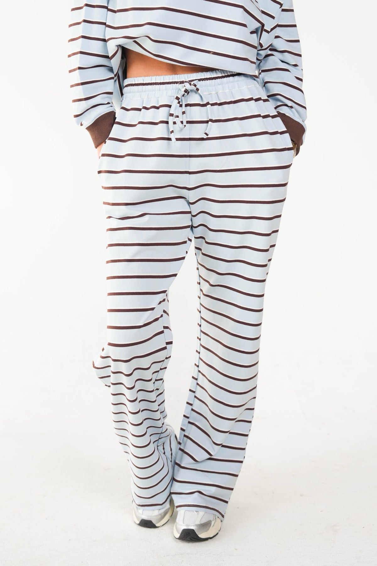 A person wearing a matching striped lounge set with a cropped long-sleeve top and wide-leg pants, shown from the waist down against a plain white studio background.