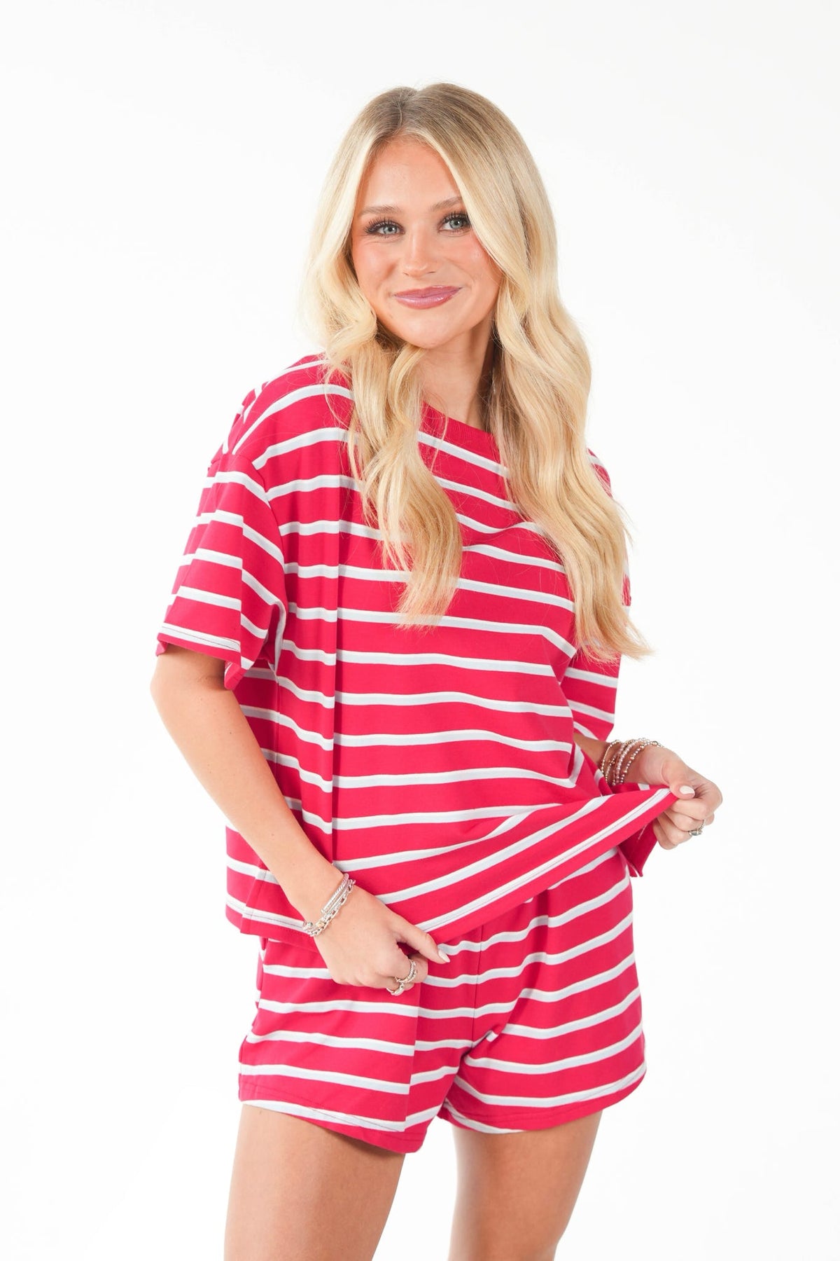 A blonde woman modeling a matching red and white striped short-sleeve top and shorts set against a plain white background.