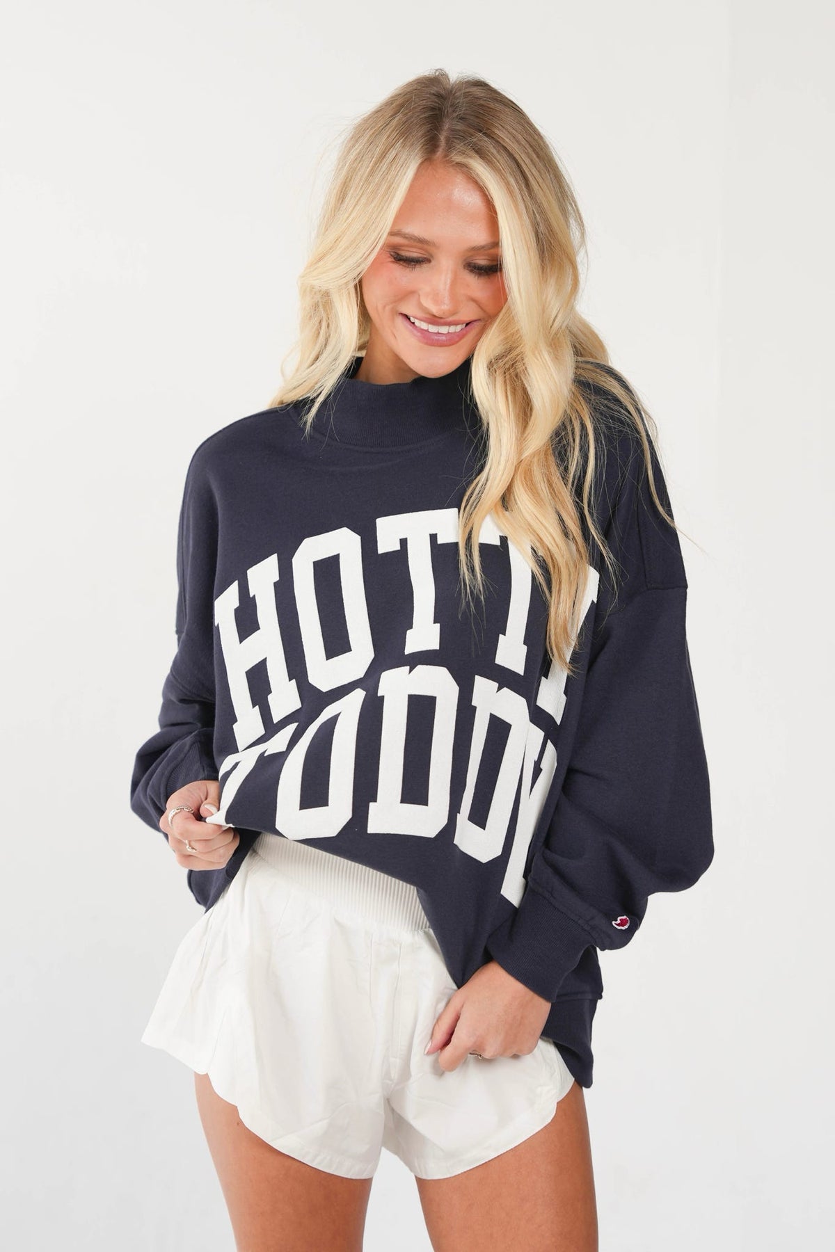 A woman wearing a navy blue sweatshirt with 'HOT TOGETHER' printed in large white letters across the front, paired with white shorts, against a plain white background.