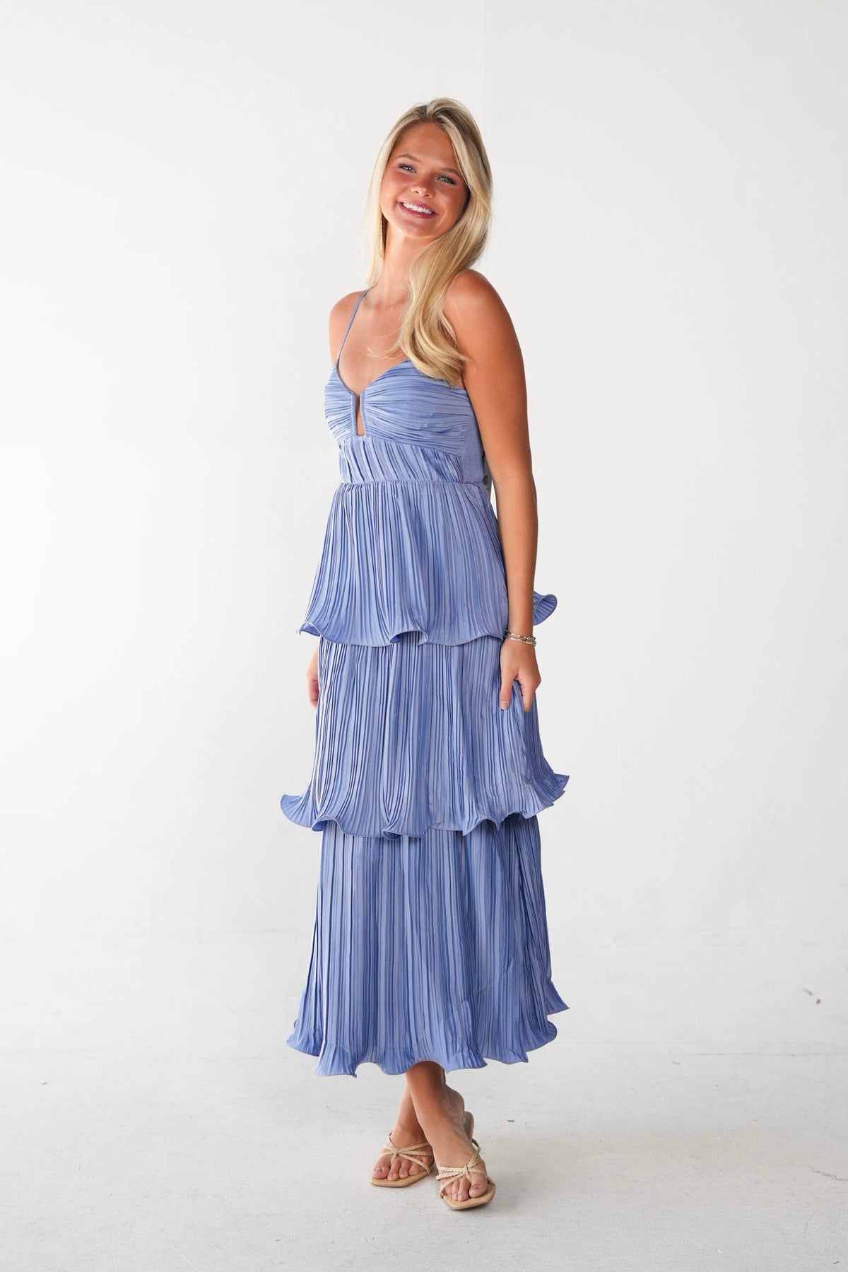 Woman wearing a blue tiered dress on a white background.