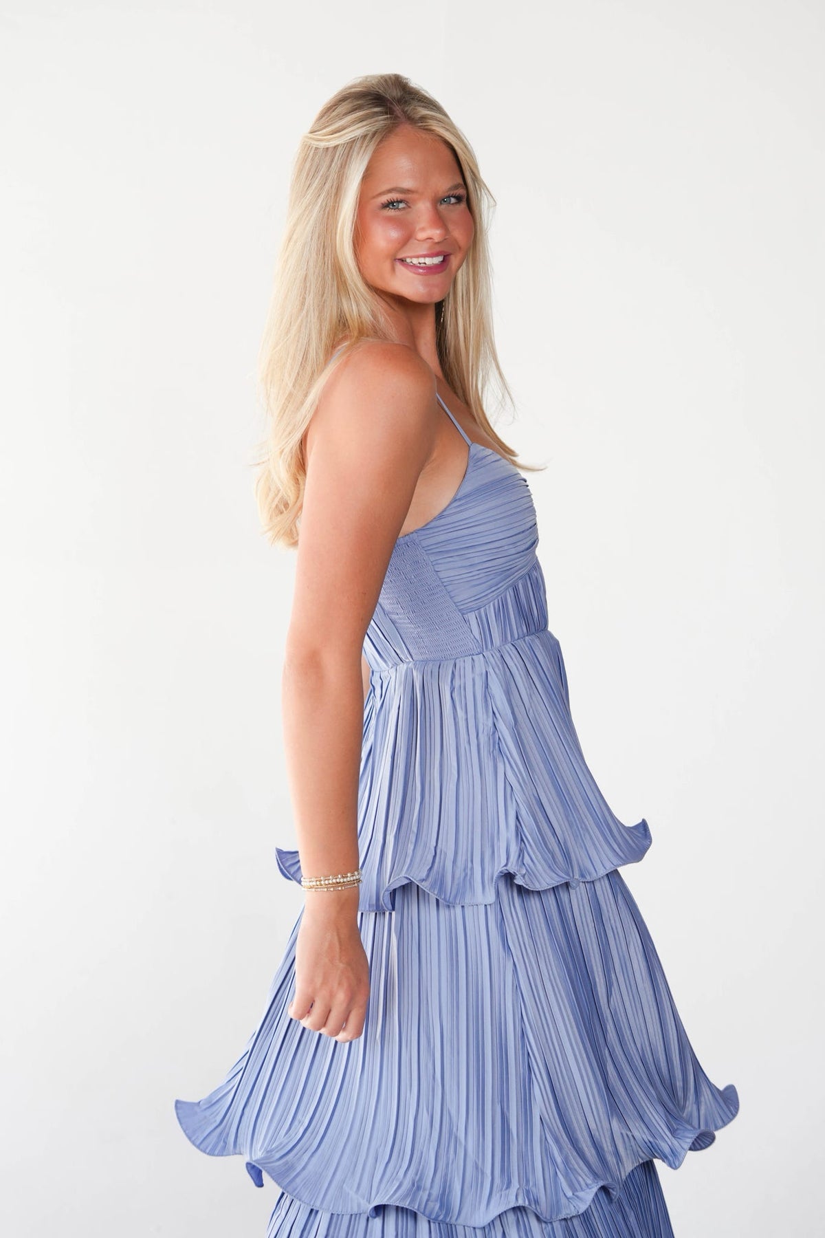 Woman wearing a blue tiered dress on a white background.