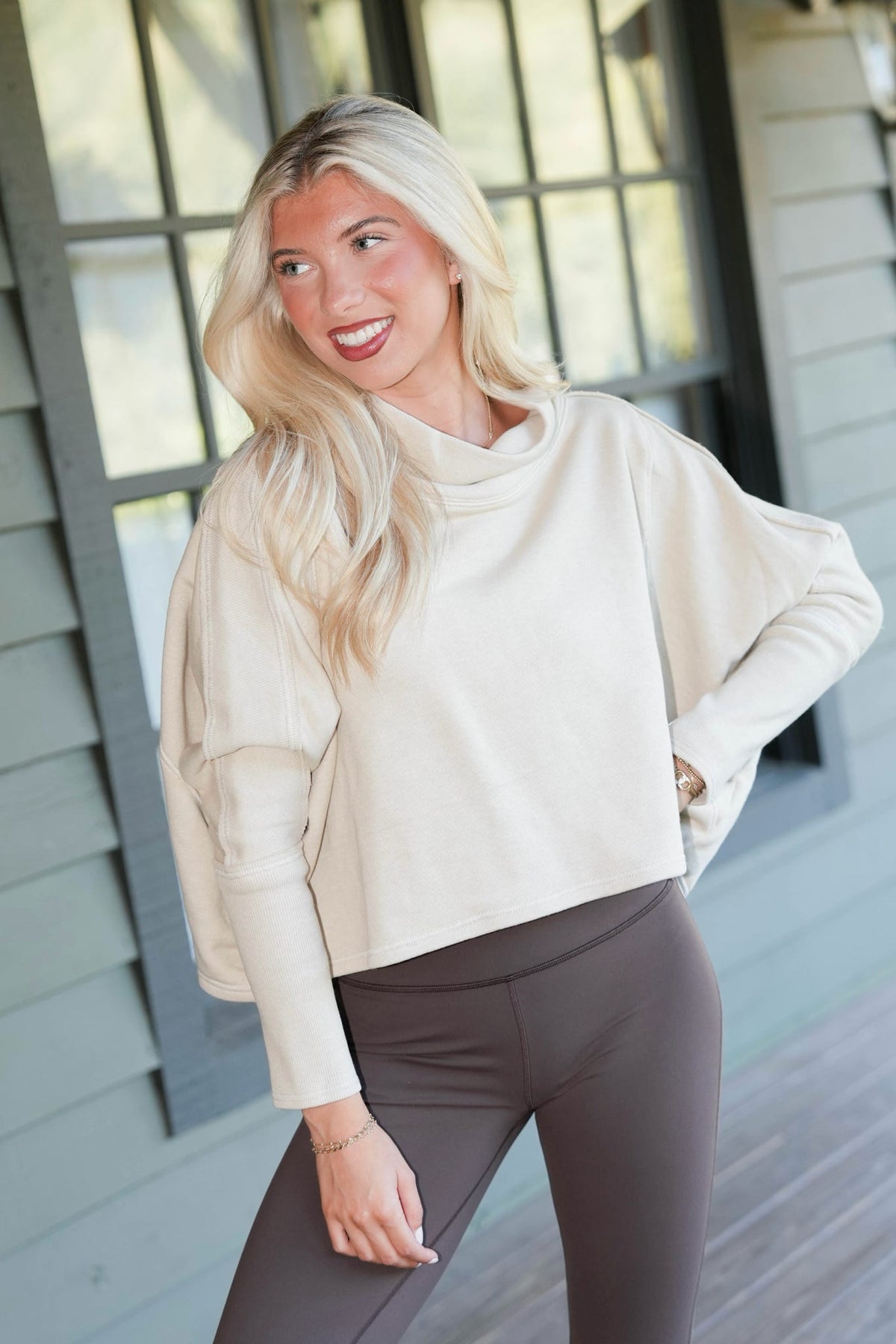woman wearing cowl neck crop sweatshirt on a porch 