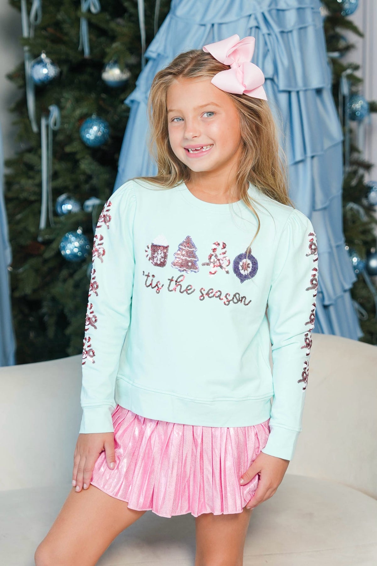 Girl wearing mint blue Long sleeve with sequin tis the season writing 