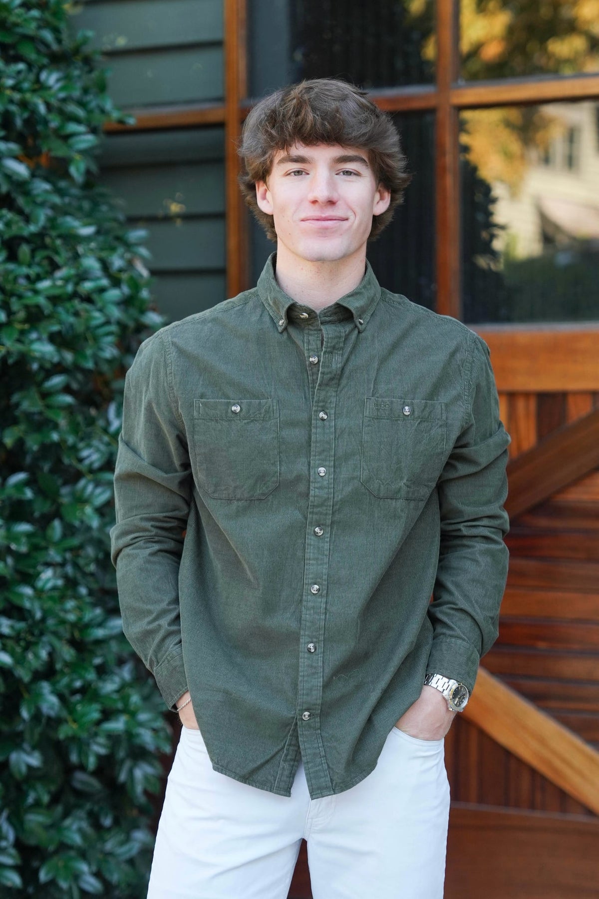 Man standing in front of a barn door wearing green button downs with jeans 