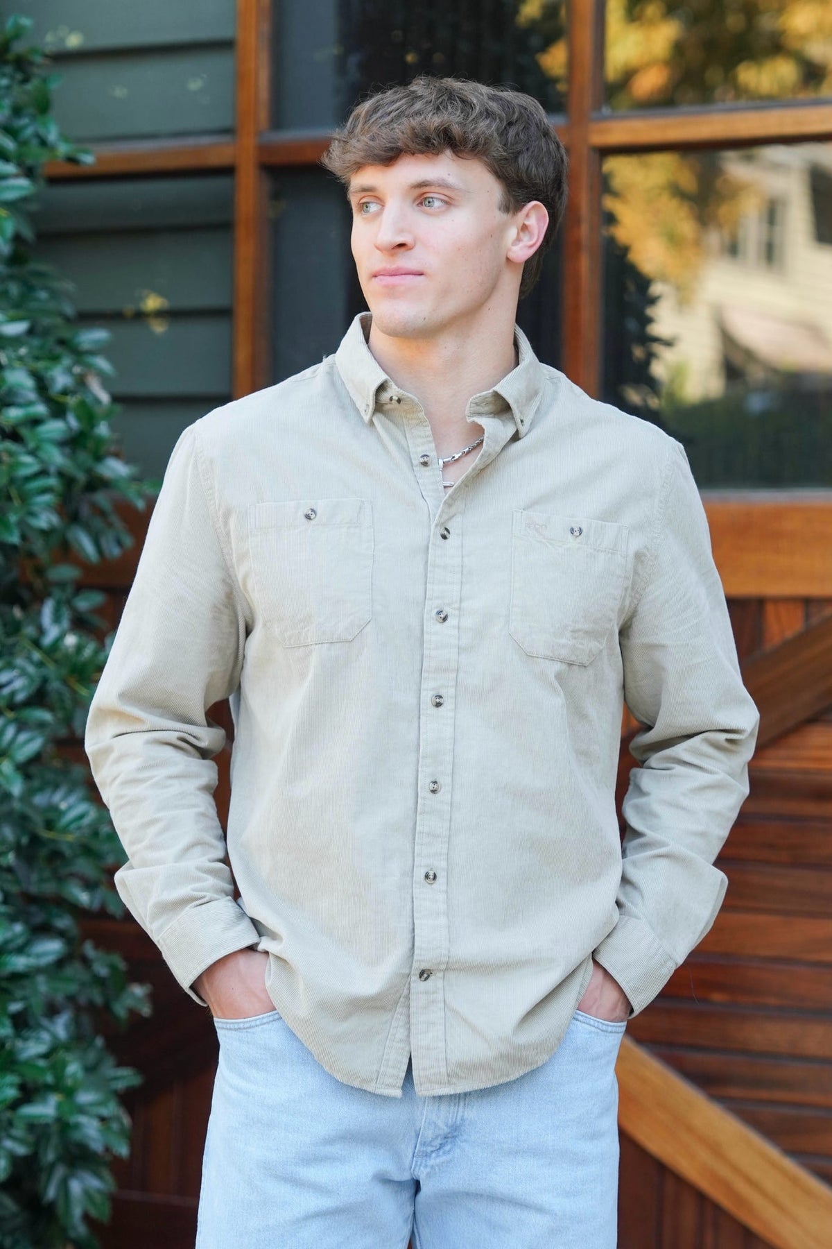 Man standing in front of a barn door wearing green button downs with jeans 