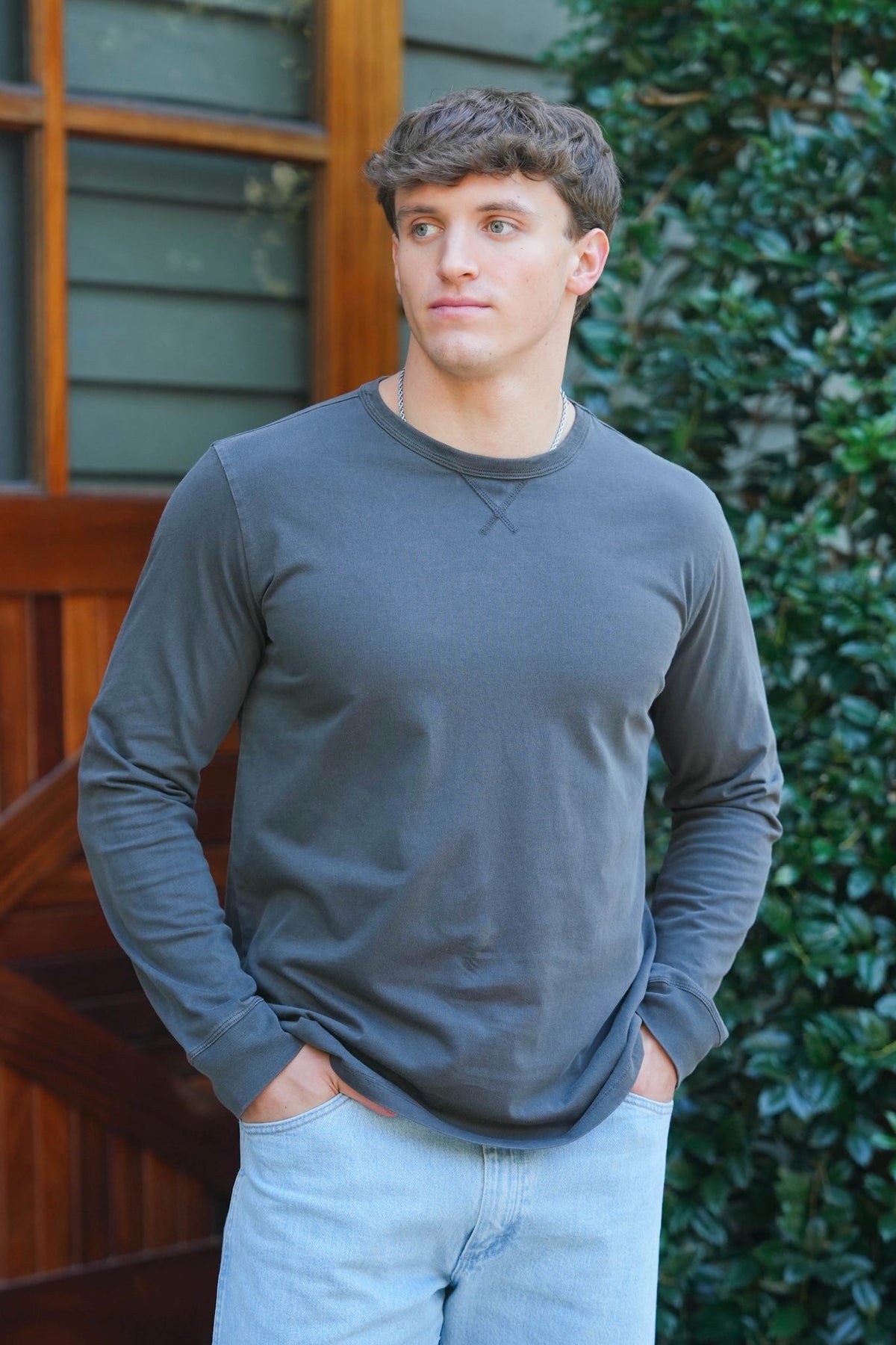 man modeling charcoal long sleeve tee with light wash denim 
