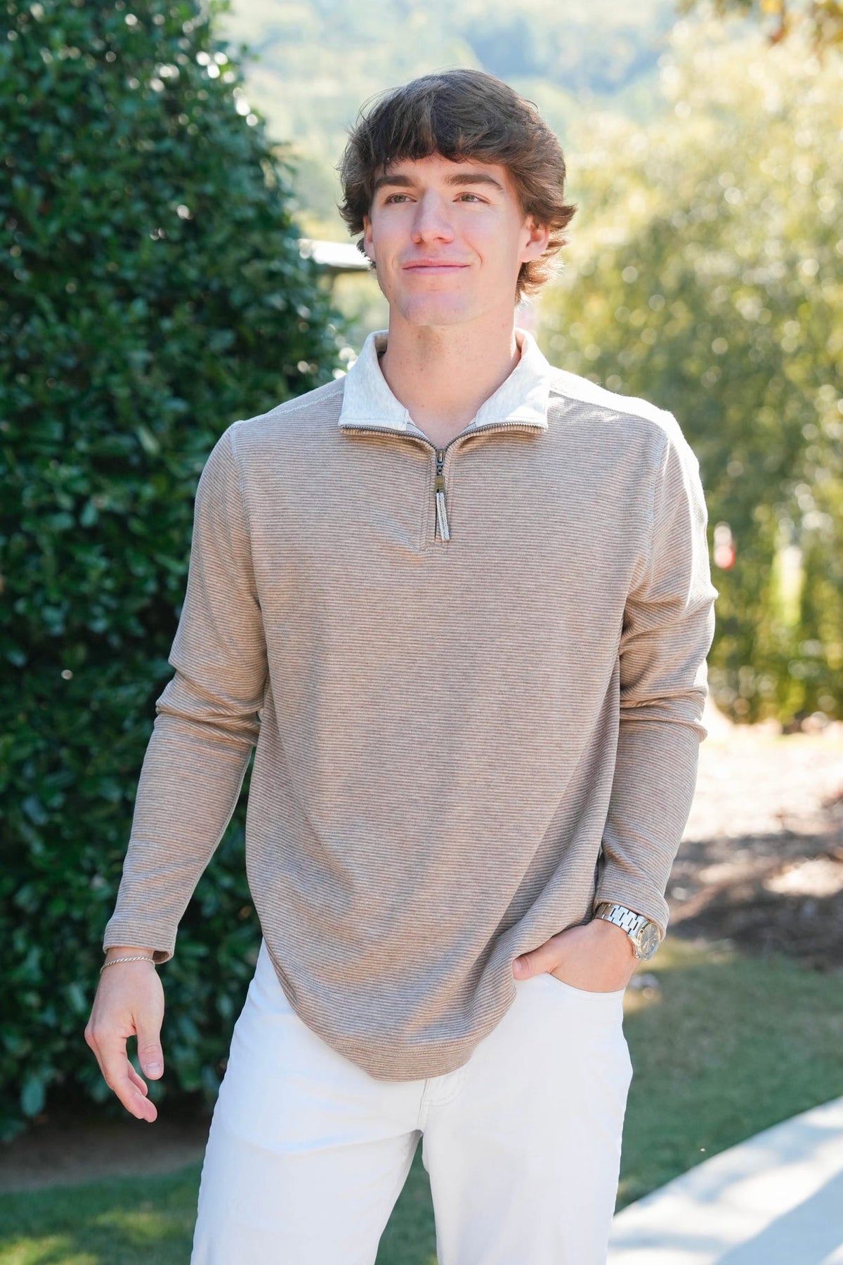 man in a brown quarter zip outdoors