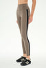 A model wearing high-waisted, full-length athletic leggings in a taupe brown color, paired with black sneakers, shown from the waist down against a plain white studio background.