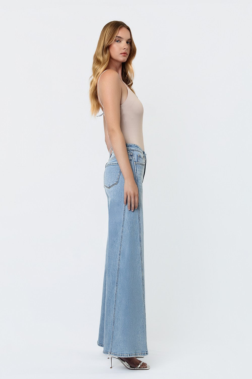 woman standing against a white background modeling a wide leg pair of jeans