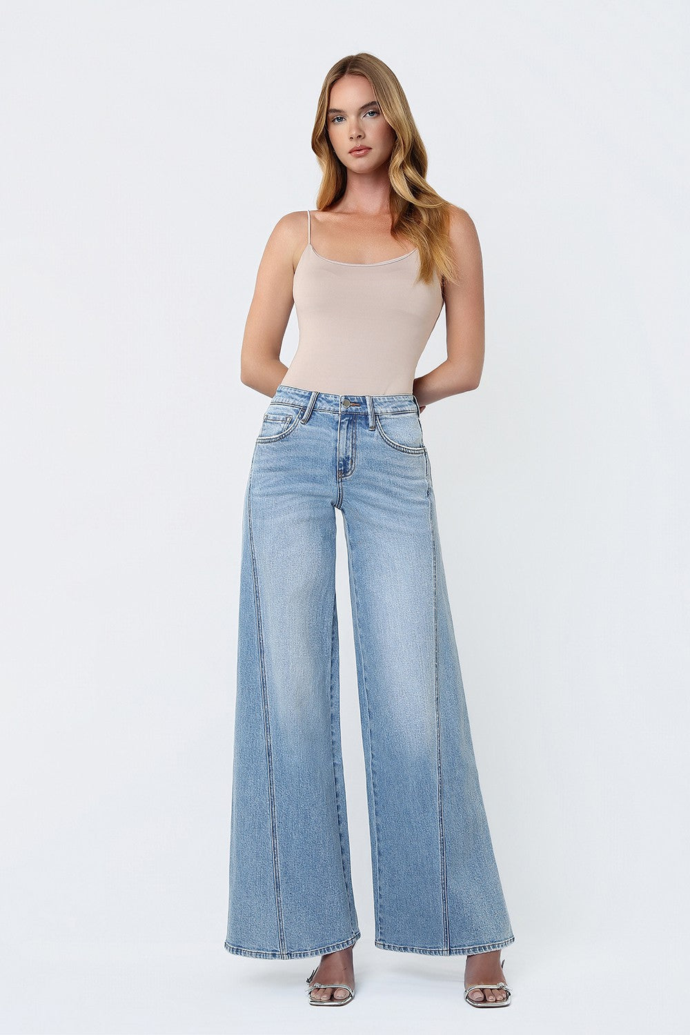 woman standing against a white background modeling a wide leg pair of jeans