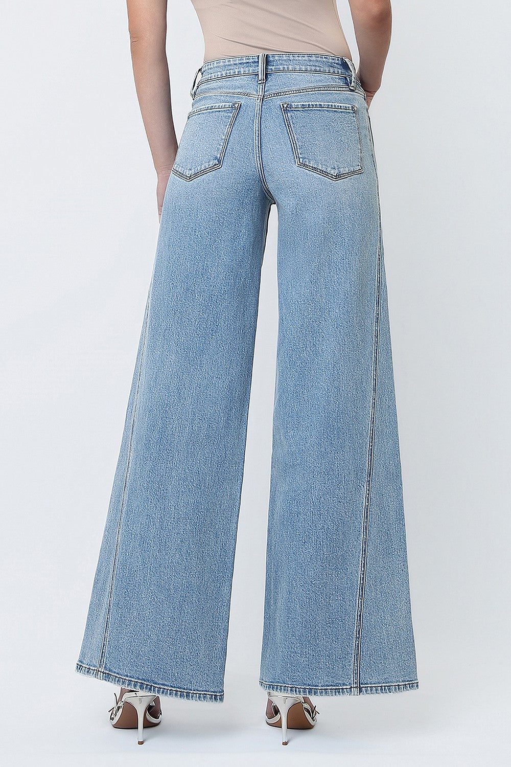 woman standing against a white background modeling a wide leg pair of jeans