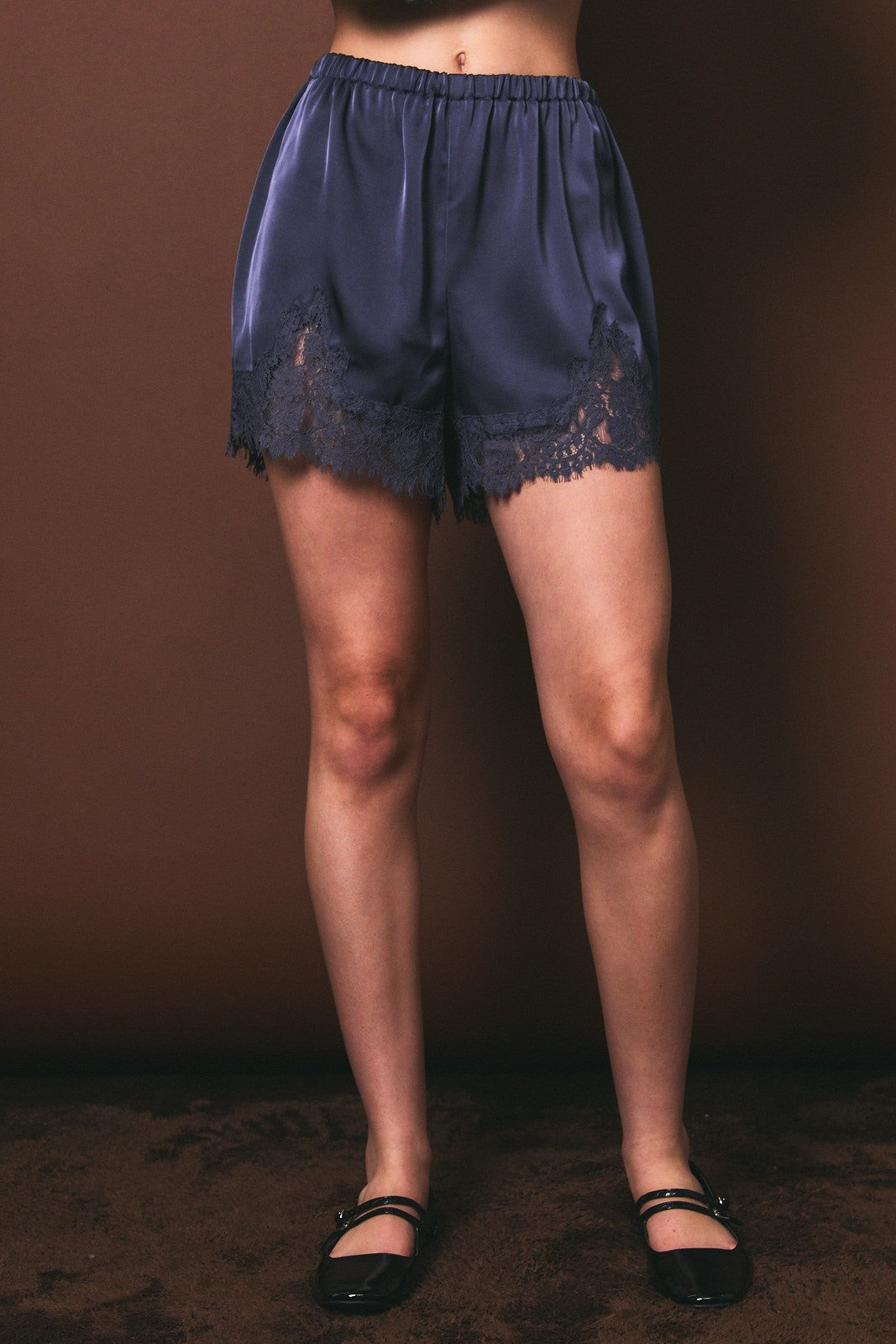Navy lace shorts worn by a person on a brown background