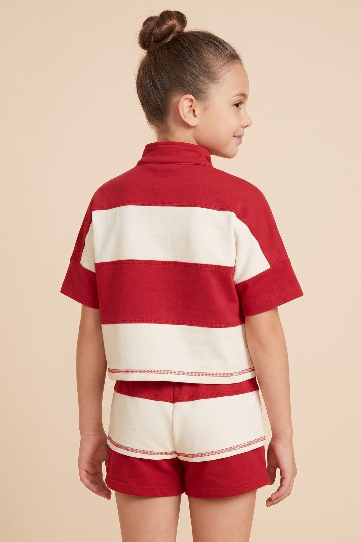 Child wearing a red and white striped outfit on a beige background