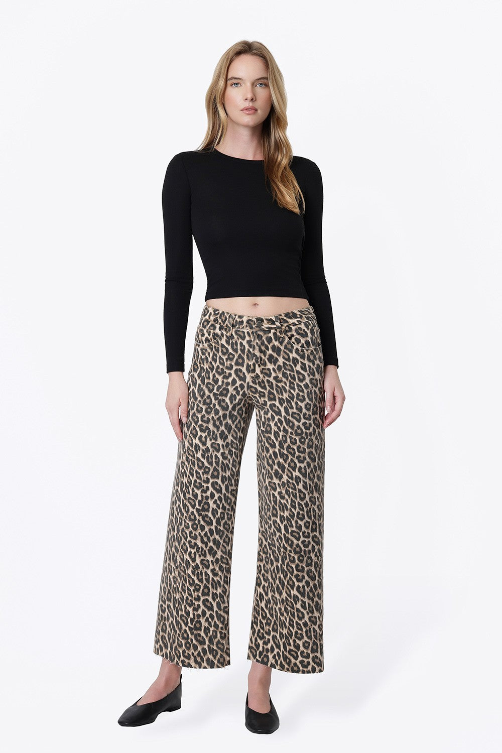woman standing against white background wearing animal print wide leg denim with black long sleeve shirt and black flats