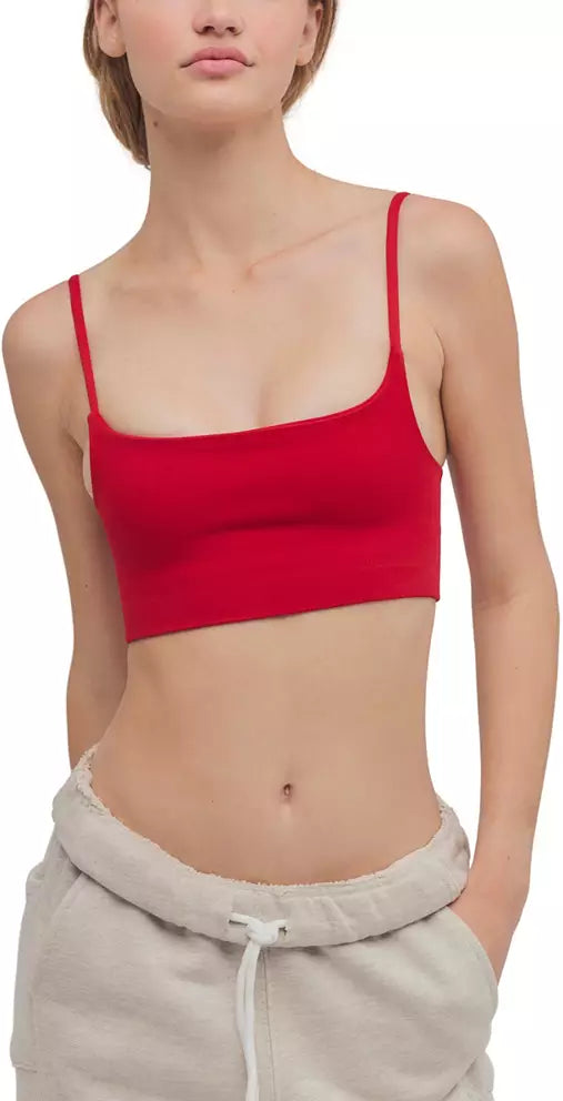 woman standing on white background wearing a red bra top and beige sweatpants