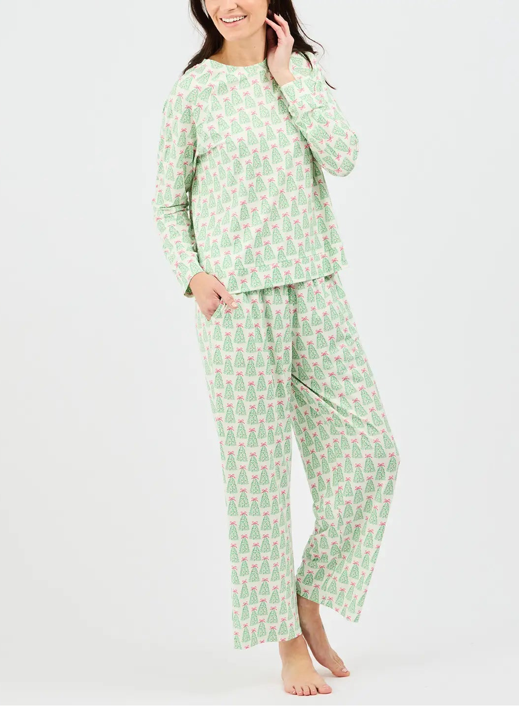 A woman modeling a two-piece long-sleeve pajama set with a light green and white geometric pattern, photographed against a plain light gray studio background.