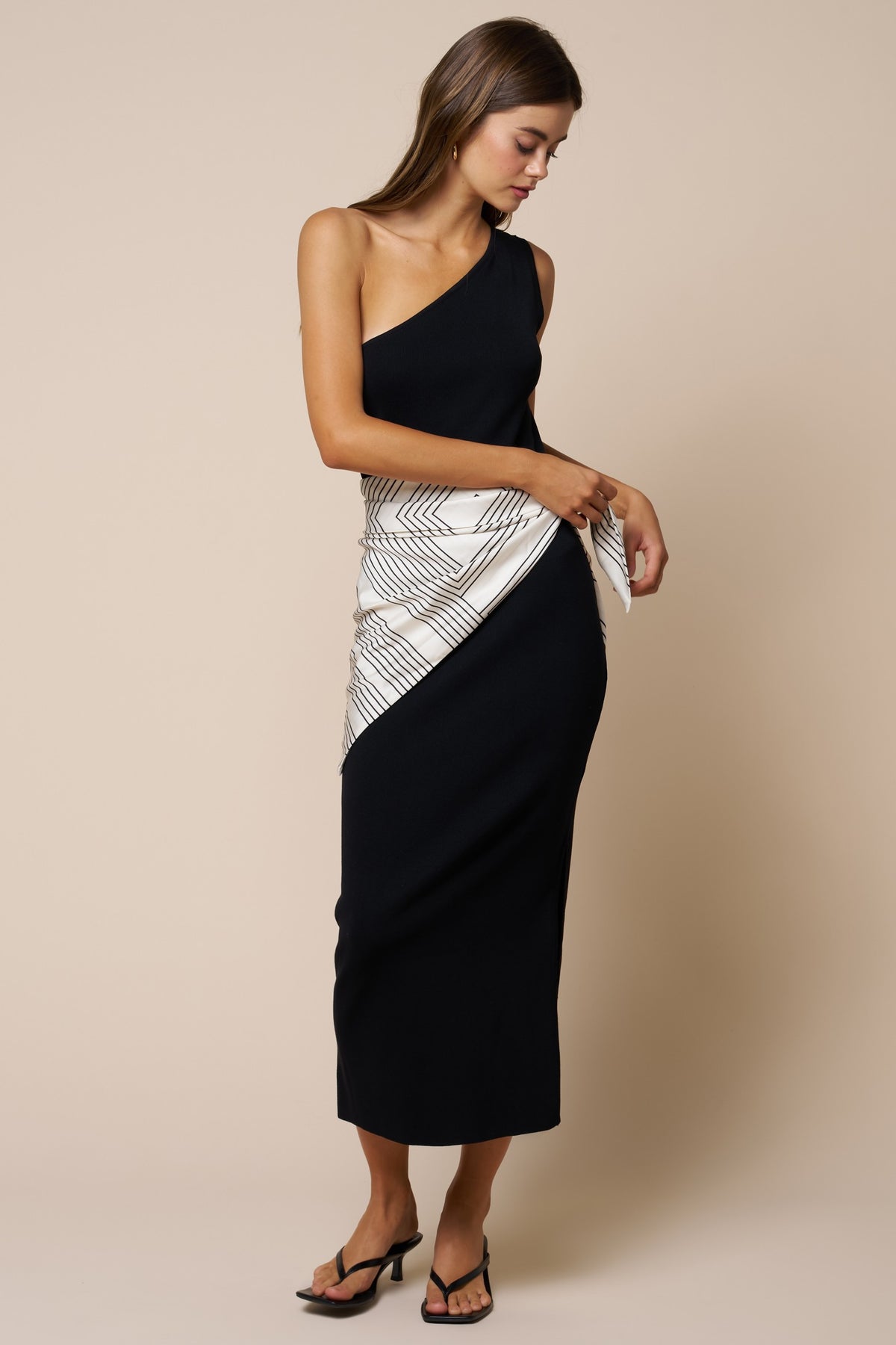 woman modeling black dress with white scarf around waist 