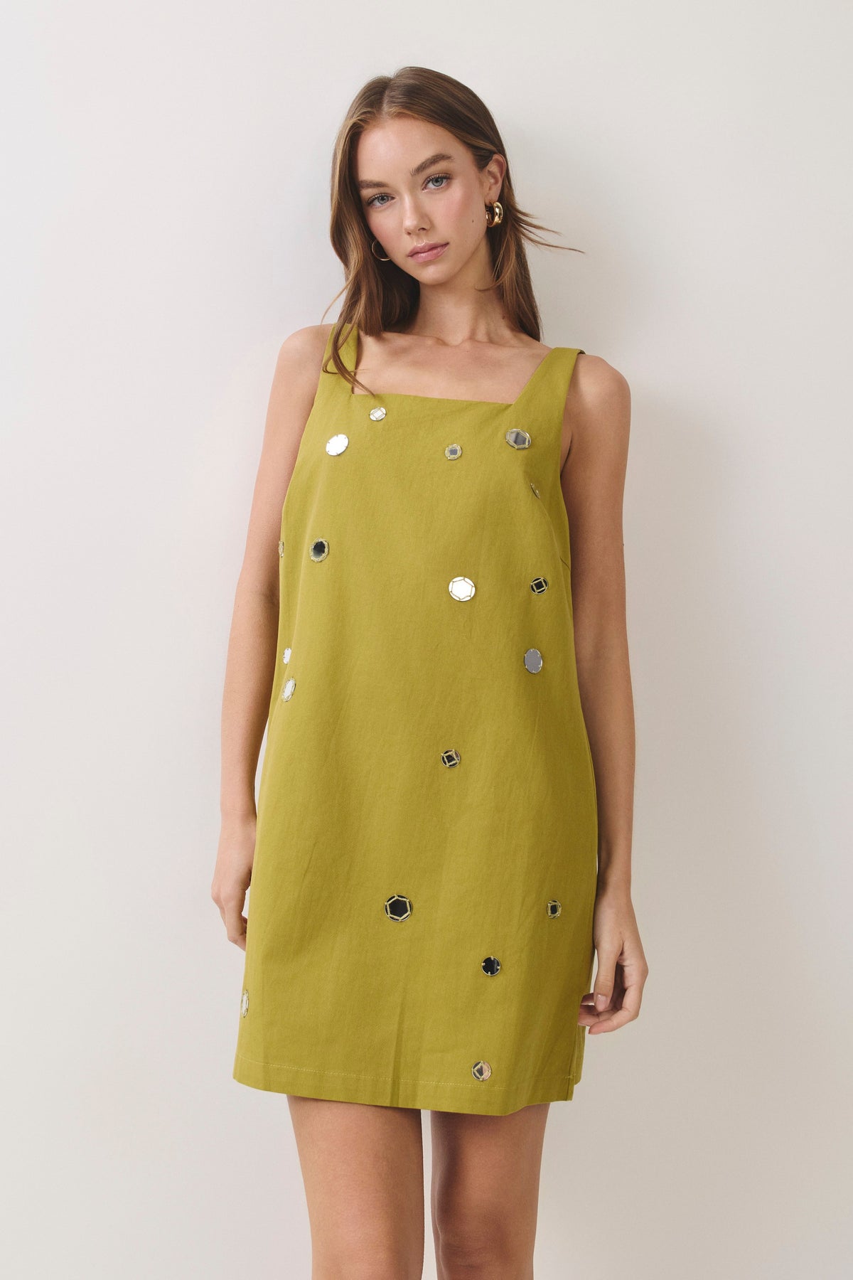 woman standing on white background wearing a green dress
