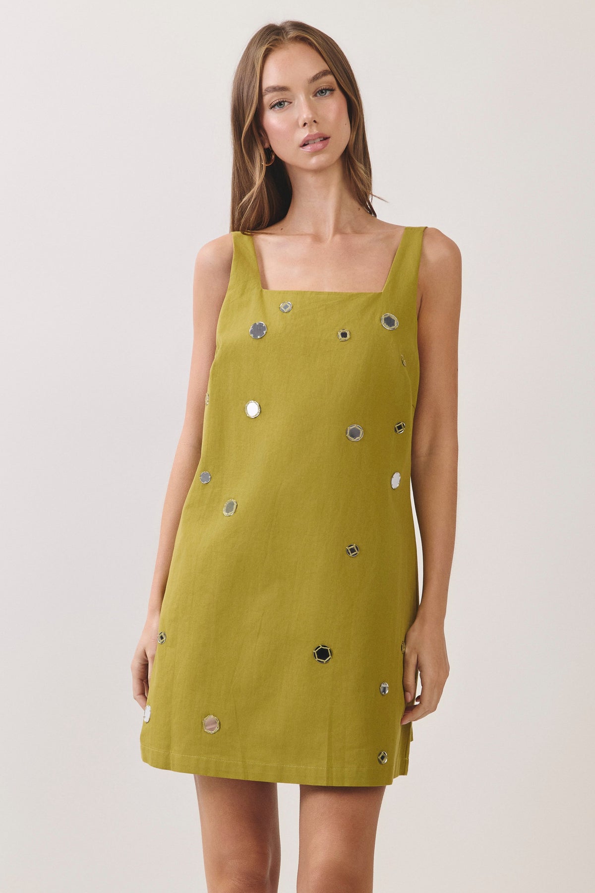 woman standing on white background wearing a green dress