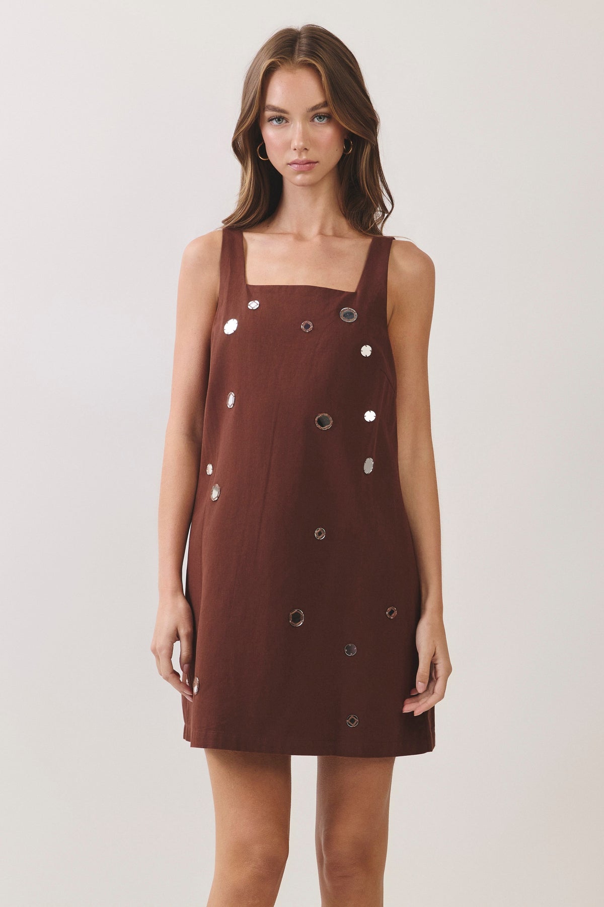 woman standing on white background wearing a brown dress