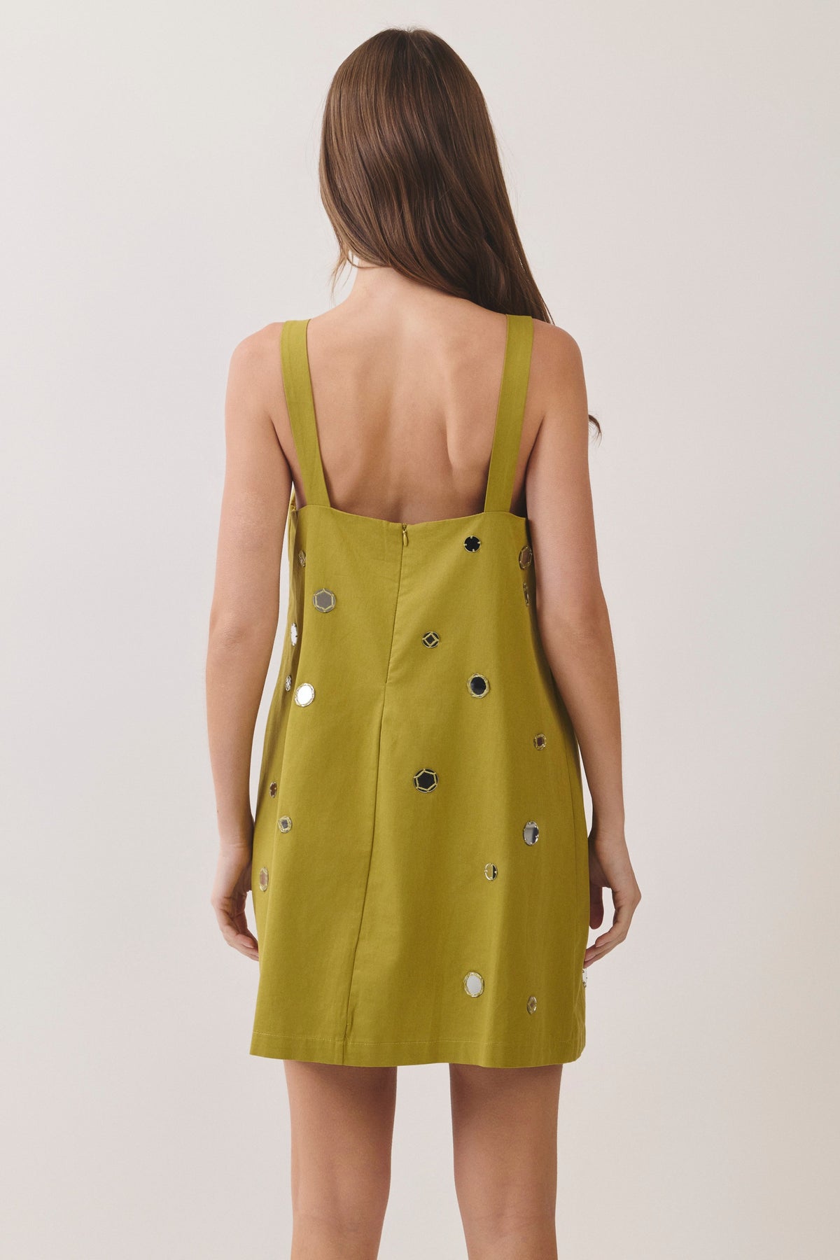 woman standing on white background wearing a green dress