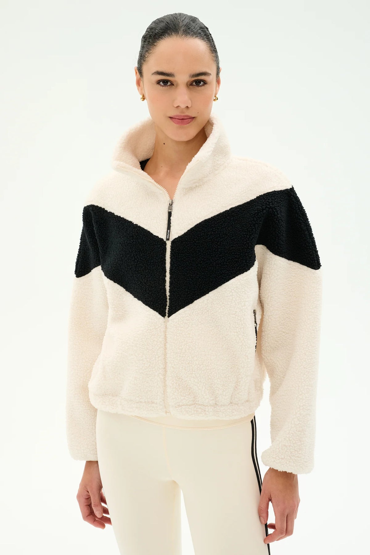 Woman modeling cream and black jacket with cream leggings