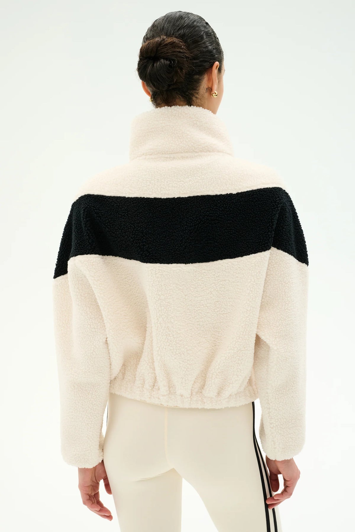 Woman modeling cream and black jacket with cream leggings